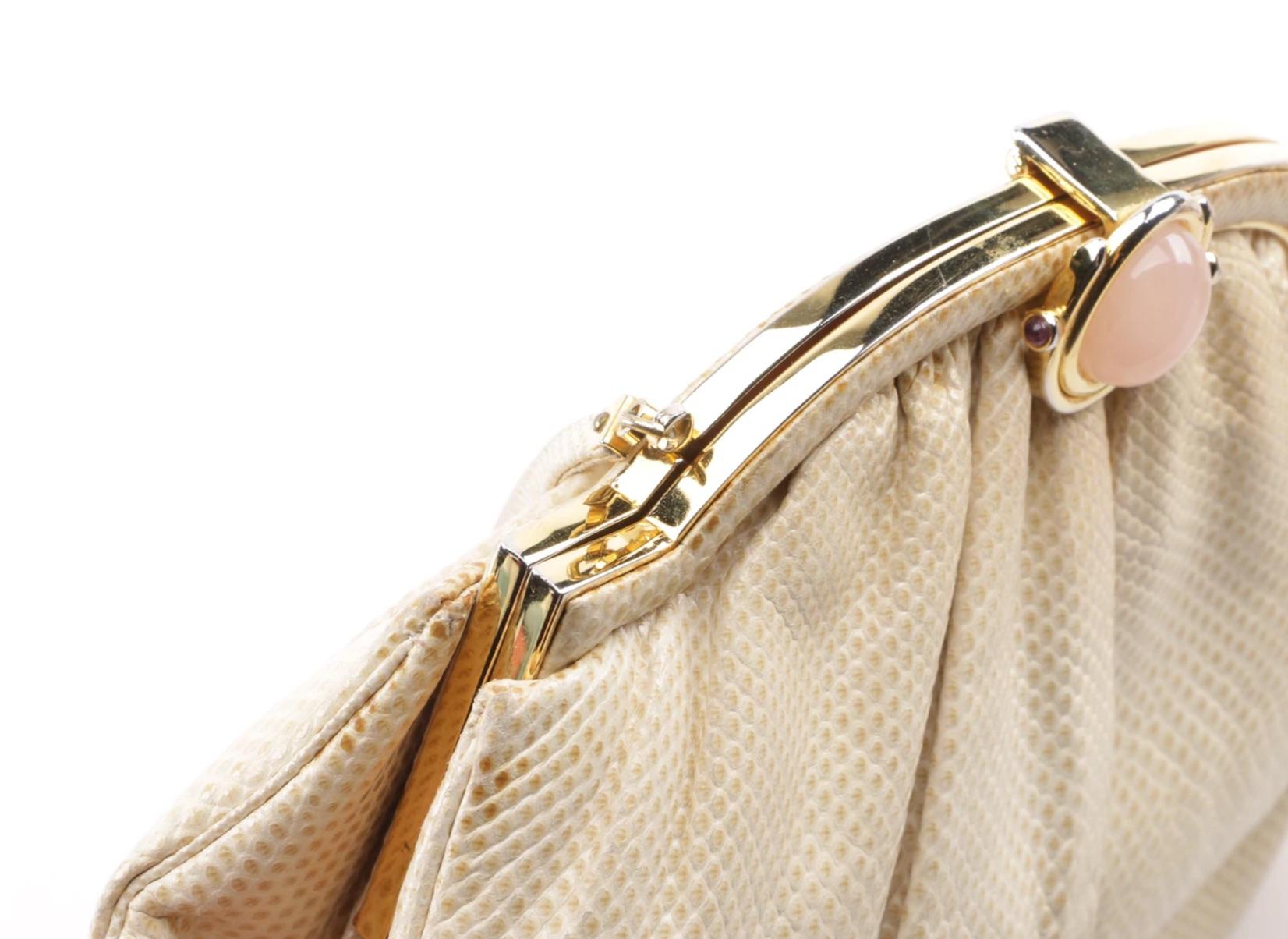 An early lovely sophisticated Judith Leiber cream karung snakeskin purse. The bag is styled with a gold tone hinged frame with a fold-over clasp featuring an oval framed Rose Quartz Cabochon, a thin shoulder strap and pleating to the body of the