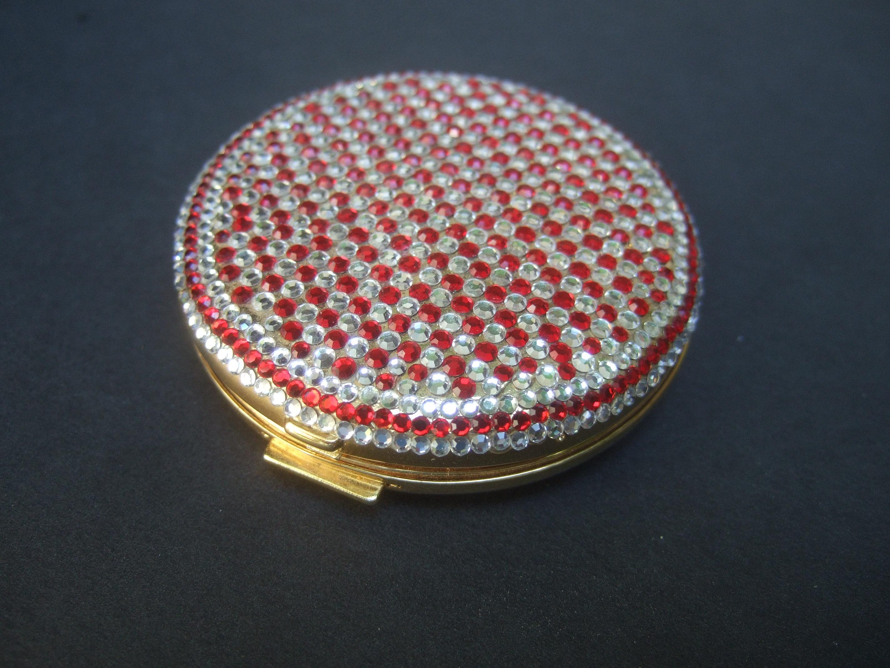 Judith Leiber Crystal encrusted vanity compact c 1980s
The elegant compact lid cover is embellished with rows of ruby red and clear diamante crystals in a geometric checkerboard pattern 

The interior is designed with a small circular vanity mirror.