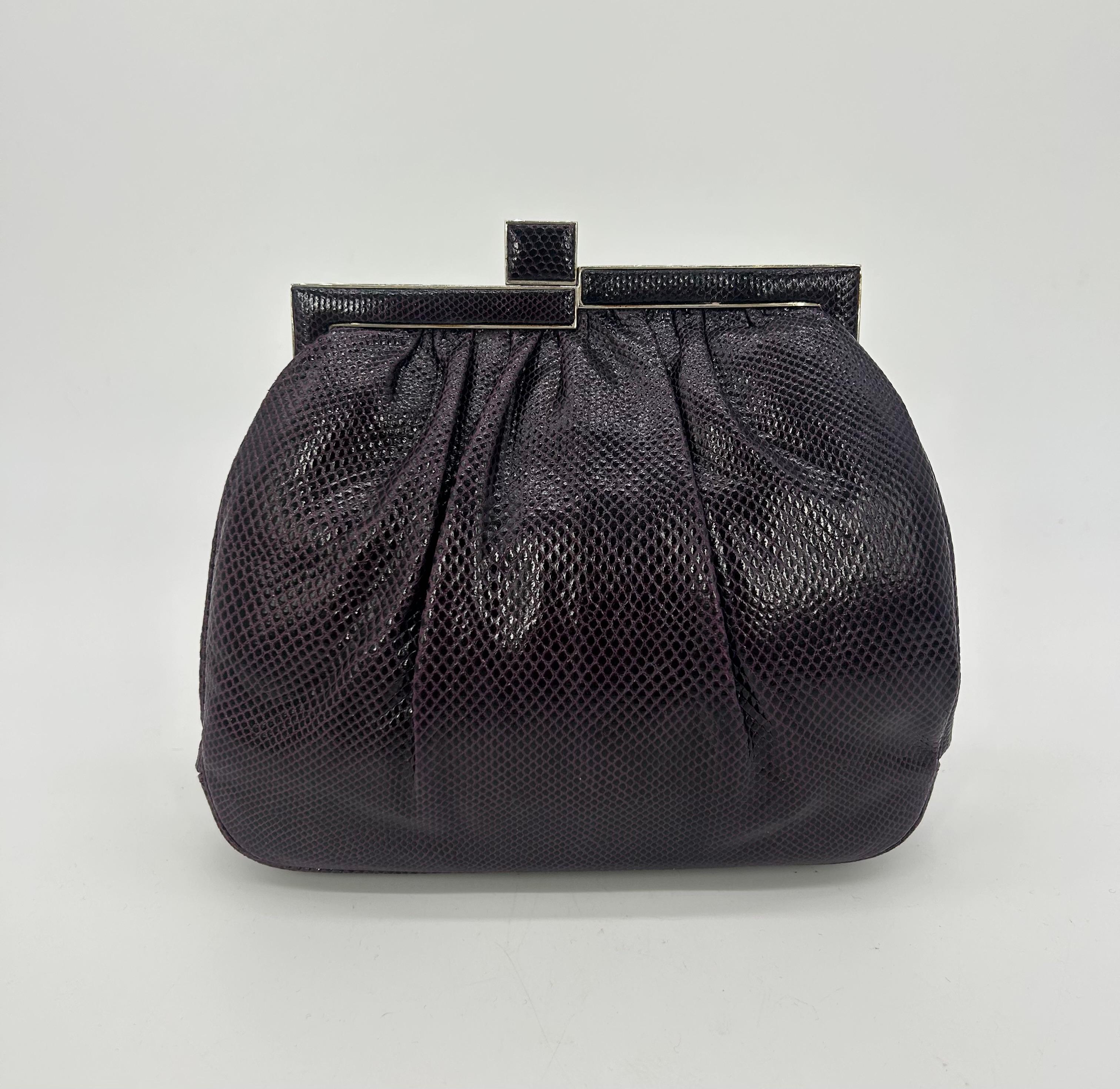 Judith Leiber dark purple lizard clutch in very good condition. Dark purple lizard leather exterior with pleats on both front and back sides. Silver hardware top edge with unique minimalist deco style design featuring small multicolored gemstones.