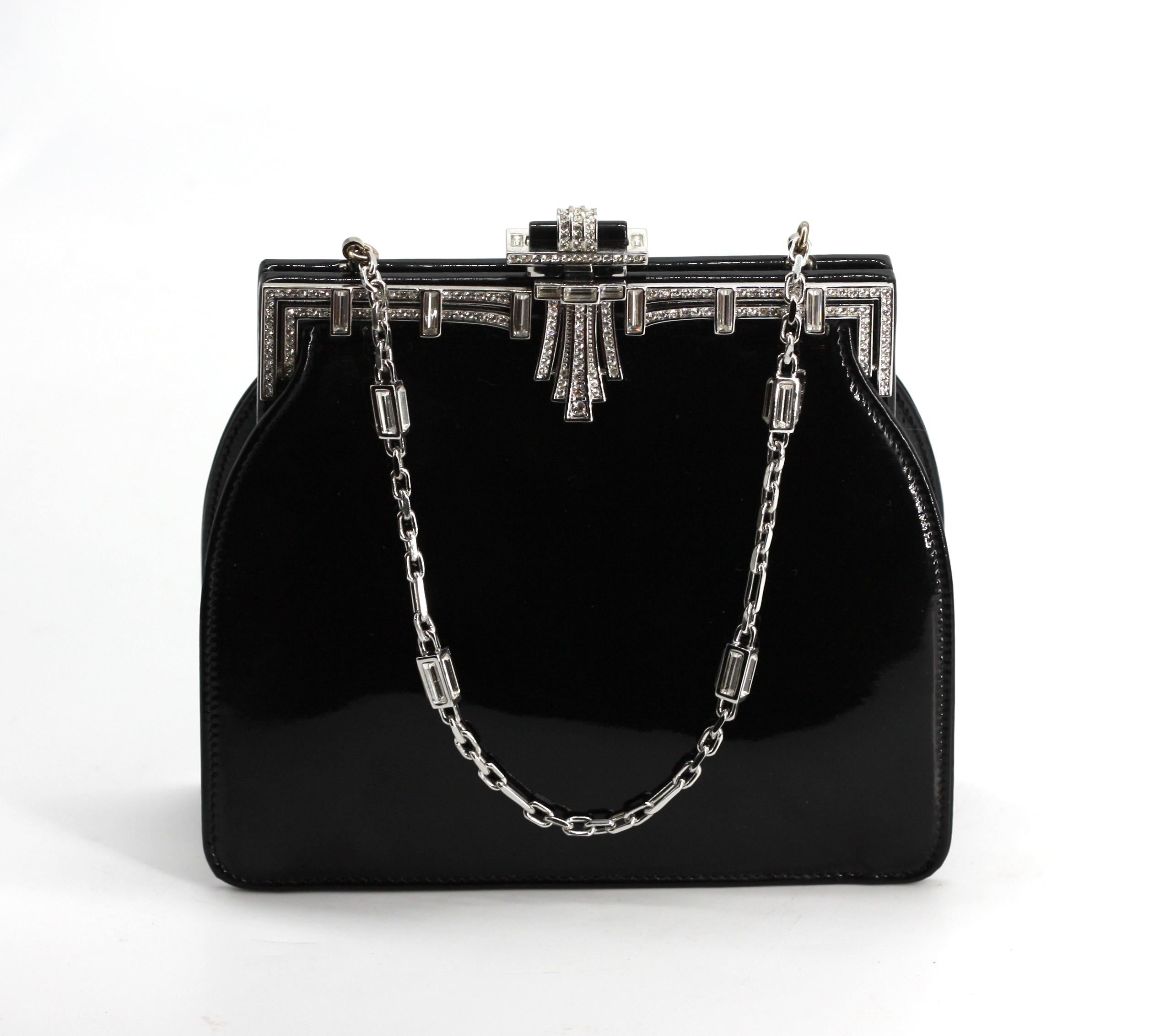 
Bolso de noche Judith Leiber de piel Patton montado con diamantes de imitación
Firmado. Cuerpo rectangular de piel patton negra con un marco ajustado de imitación de diamante y una cadena corta plateada; el interior tiene cremallera y una pequeña