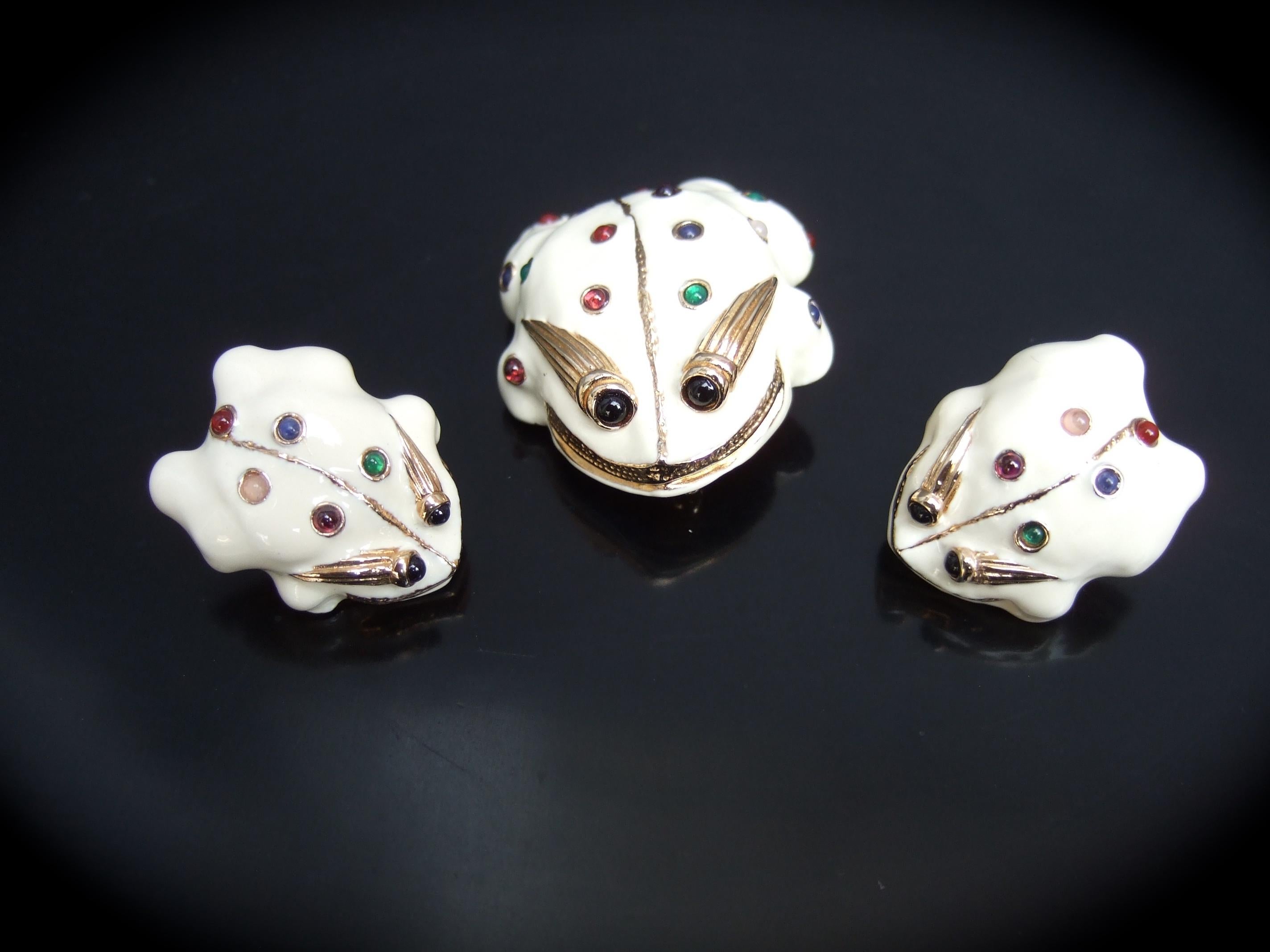Judith Leiber Charming glass cabochon white enamel frog brooch & earrings set c 1980s
The set is designed with a trio of endearing creamy white enamel frogs; embellished 
with small glass cabochons in a myriad of jewel tone colors 

The trio of