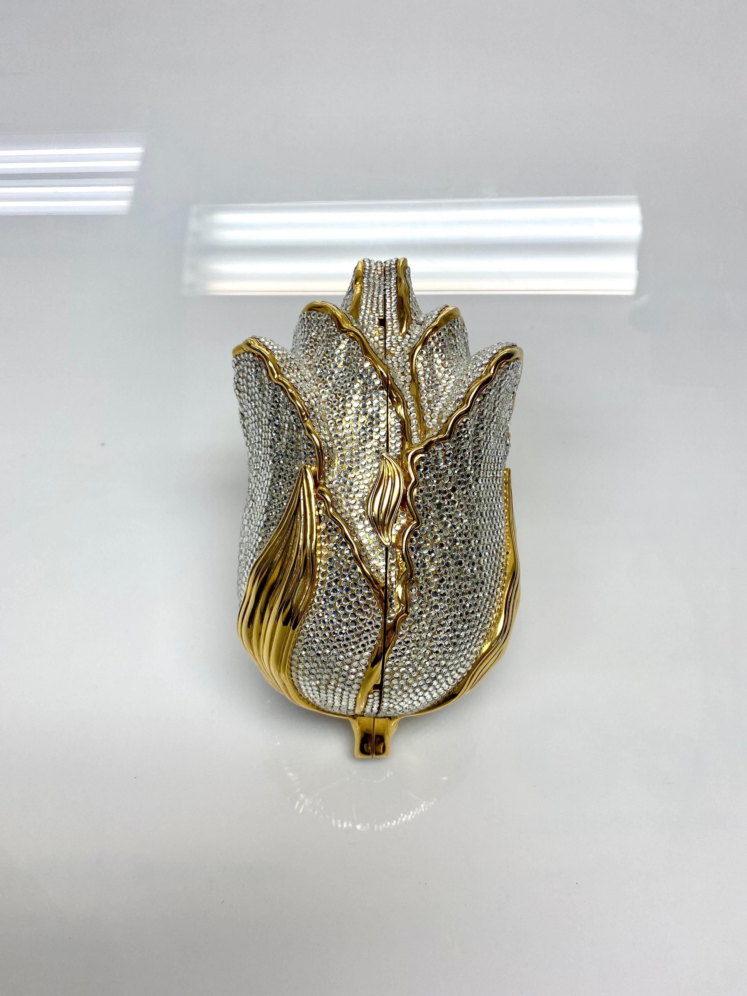 Judith Leiber Couture's signature novelty designs add a touch of whimsy to any look they're paired with. This particular creation is a beautifully mastered flower design embellished with gold and silver crystals. The compact design is sized to hold