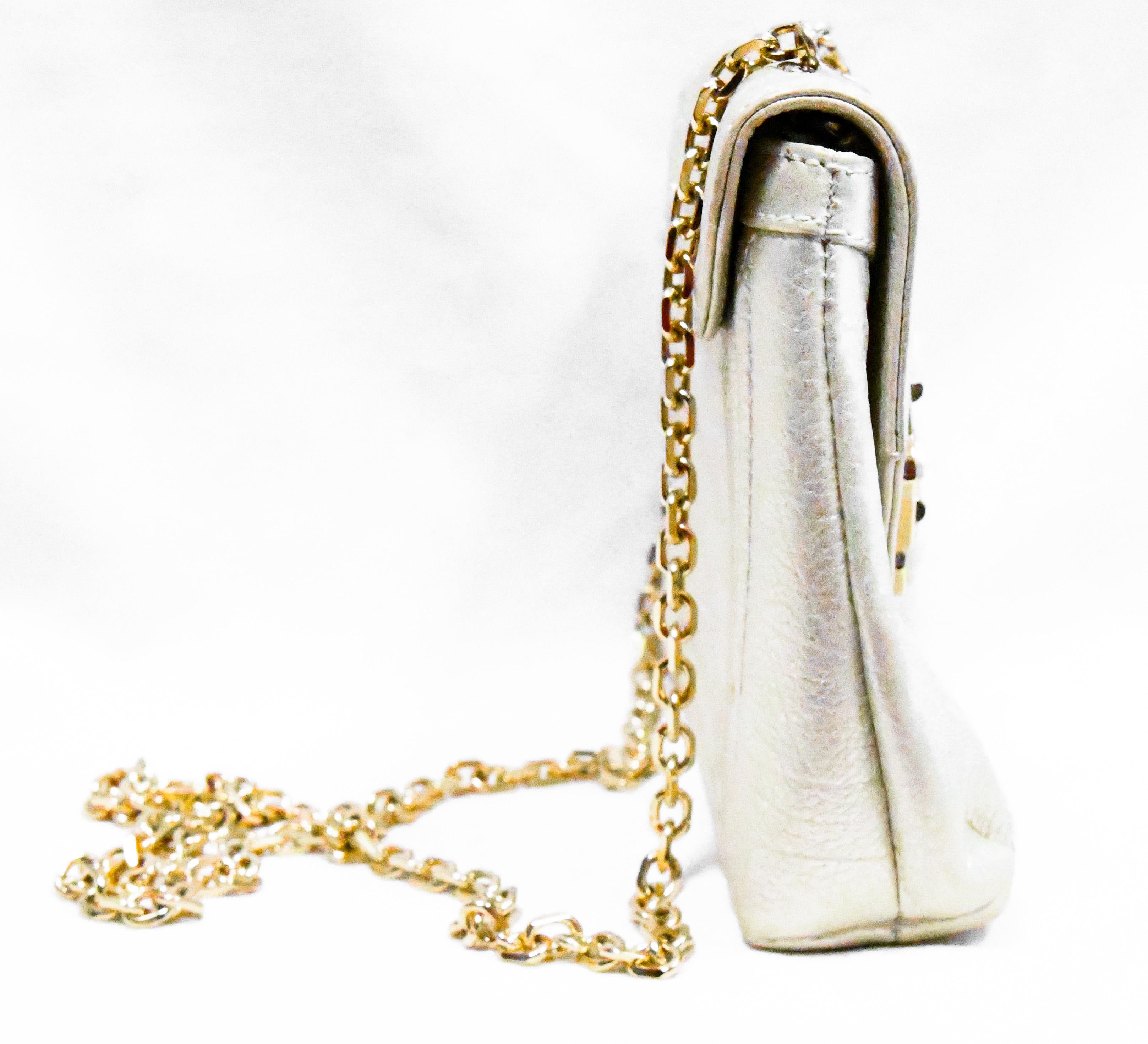 Judith Leiber metallic gold tone leather includes bold chain link strap that can be removed to use as a clutch.  The Art Deco closure on the flap is decorated in mother of pearl encrusted in epoxy accentuated with crystal baguettes, mini crystals