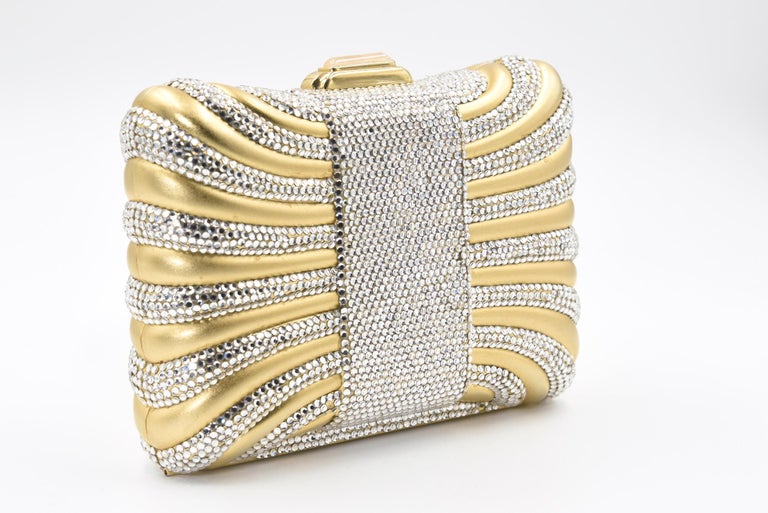 Elegant Judith Leiber minaudière looks like a gift box or pillow with a Swarovski crystal ribbon.  The bag features a press crystal lock closure with  golden hardware, The shoulder strap that can be tucked into the interior of the bag for use as a