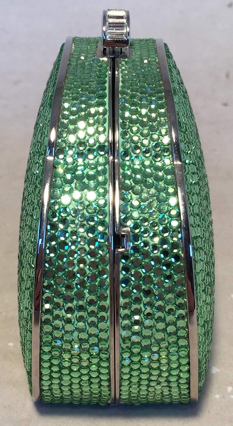 Judith Leiber Green Swarovski Crystal Minaudiere Evening Bag in excellent condition. Green swarovksi crystal exterior trimmed with silver hardware. Top button closure opens to a silver leather interior that holds an attached hidden silver chain