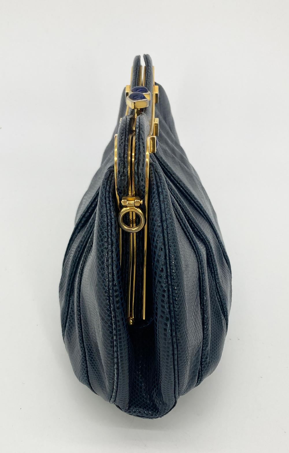 Judith Leiber Navy Lizard Clutch in very good condition. navy lizard trimmed with gold hardware and lapis gemstones along top edge. Kiss lock top closure opens to a navy nylon interior with one zip and one slit side pockets. overall very good