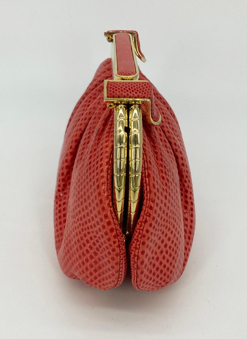Judith Leiber Red Lizard Clutch in excellent condition. Red lizard leather trimmed with gold hardware. Double latch top closure opens to a red nylon interior with one slit and one zip side pockets. attached matching lizard shoulder strap easily