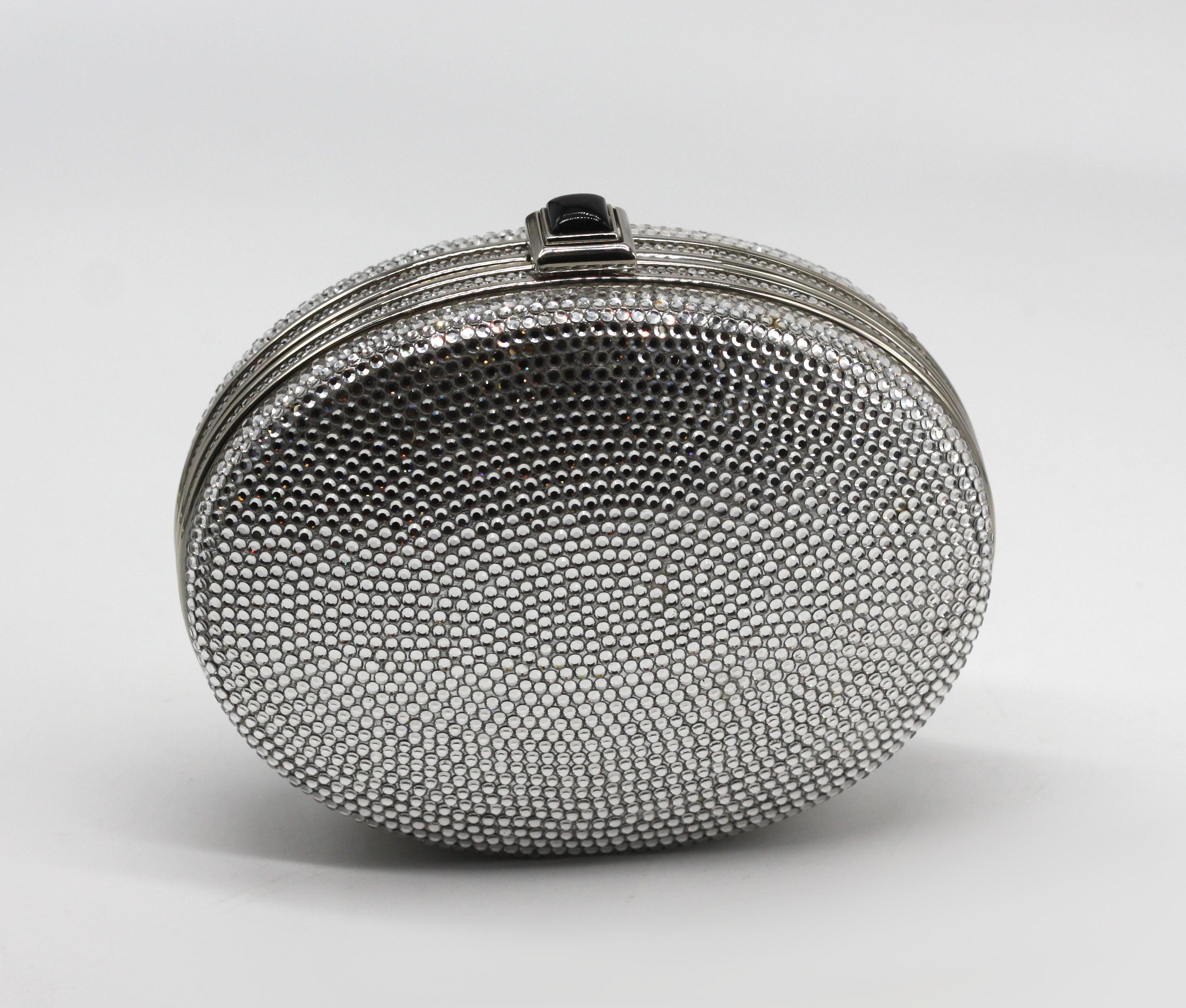 Bolso de noche Judith Leiber Minaudière plateado

De elegante forma ovalada, esta minaudière se presenta en un luminoso acabado plateado con herrajes y marco plateados, coronado por un broche de imitación de ónice. El interior, forrado en piel