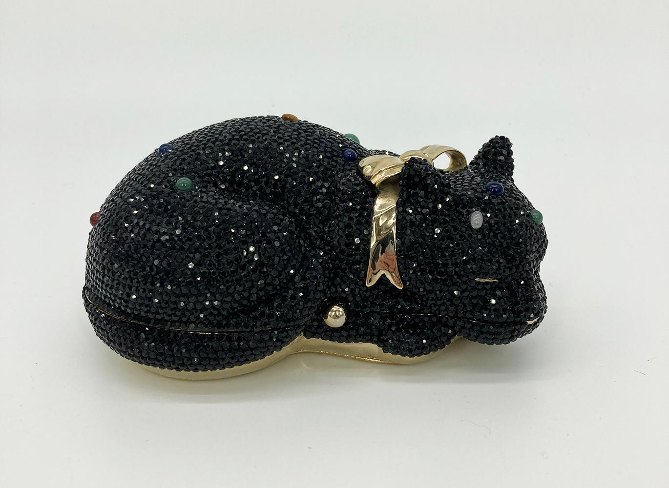 ADORABLE Vintage Judith Leiber cat minaudiere in excellent condition. Black Swarovski crystal body with multi color gemstones and gold bow accent. Gold leather exterior base. Button closure opens to a gold leather lined interior. Excellent