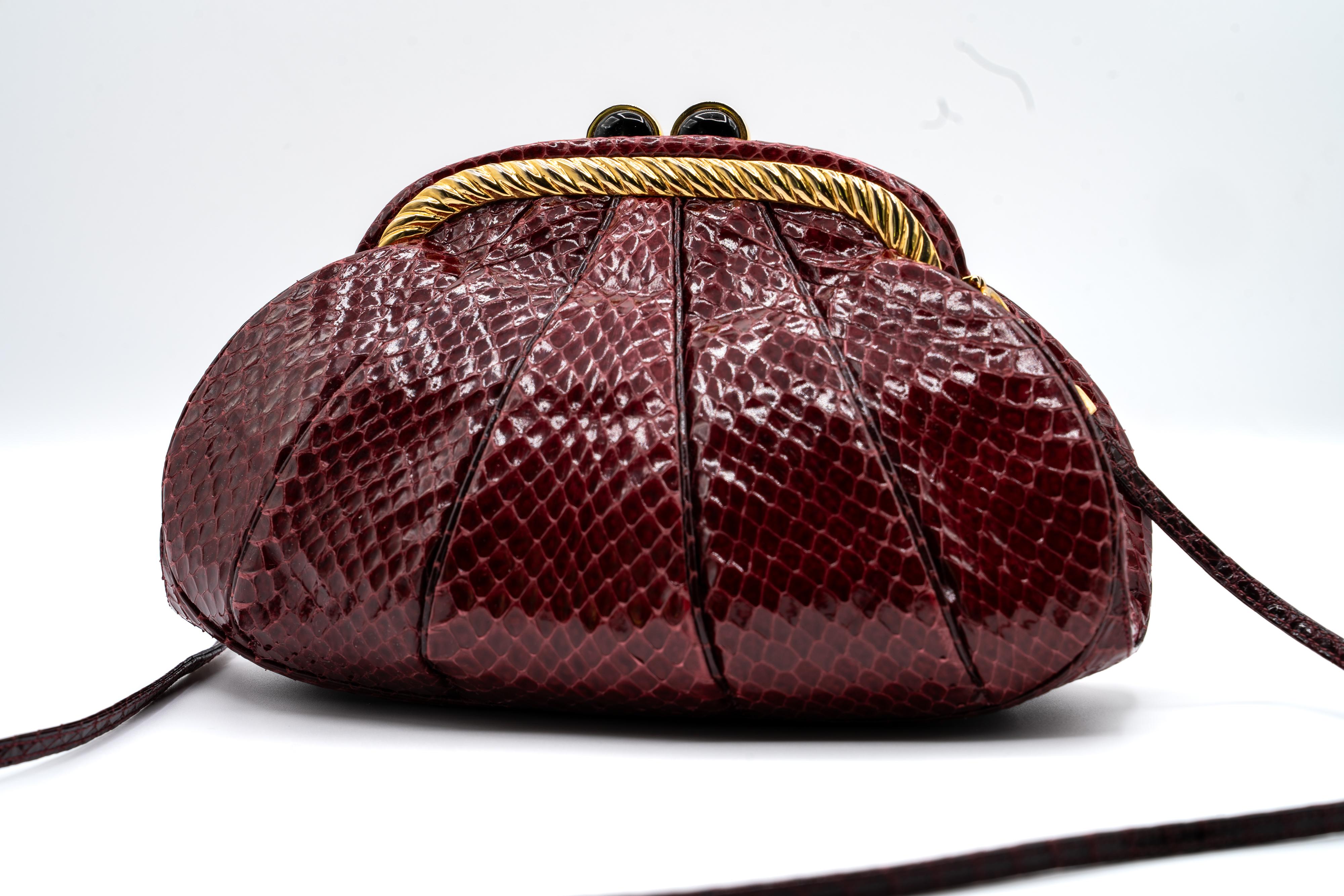 This exquisite Judith Leiber handbag showcases luxurious burgundy snakeskin with a structured, pleated design. Its gold-tone metal frame features an elegant twisted rope detail, complemented by a signature bordeaux cabochon clasp.

Designed for
