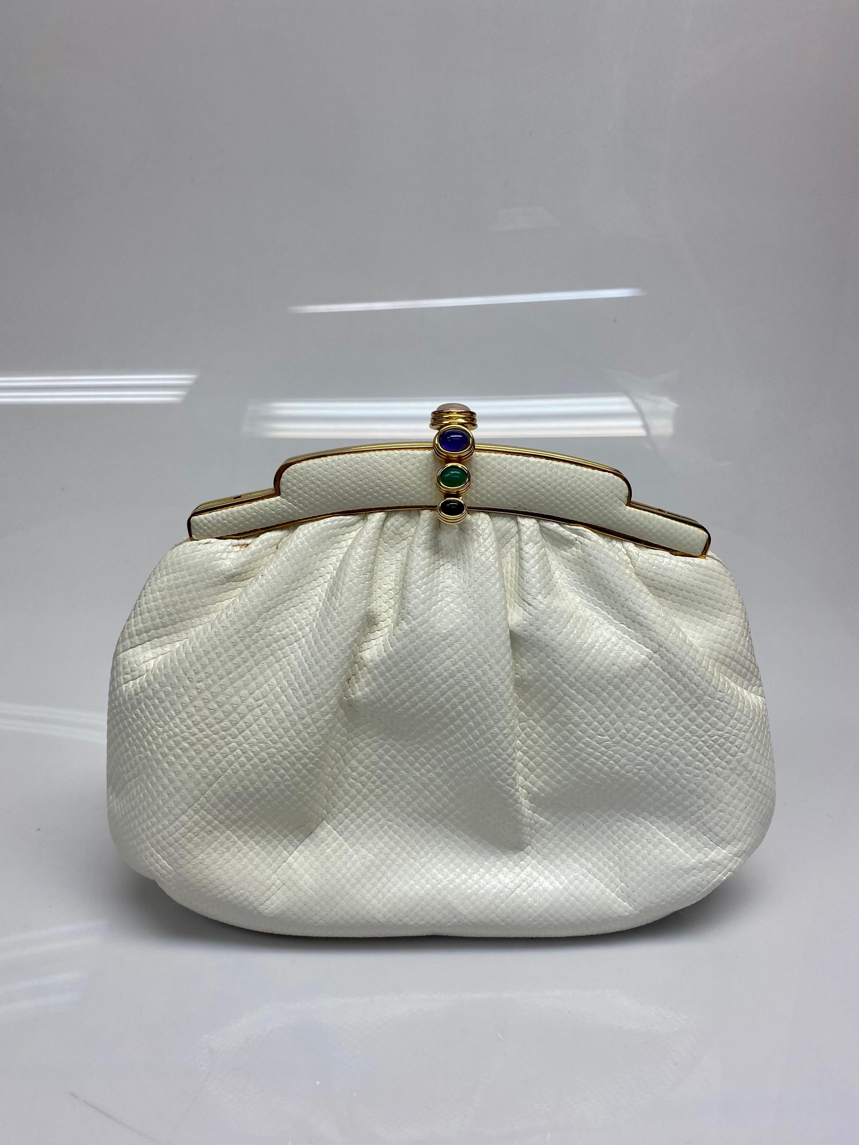 This beautiful Judith Leiber Lizard handbag can be worn as a clutch or a crossbody and is perfect with any outfit. The bag features gold hardware with a 4 stone multi colored jeweled closure. The vintage bag is in good condition with some stains