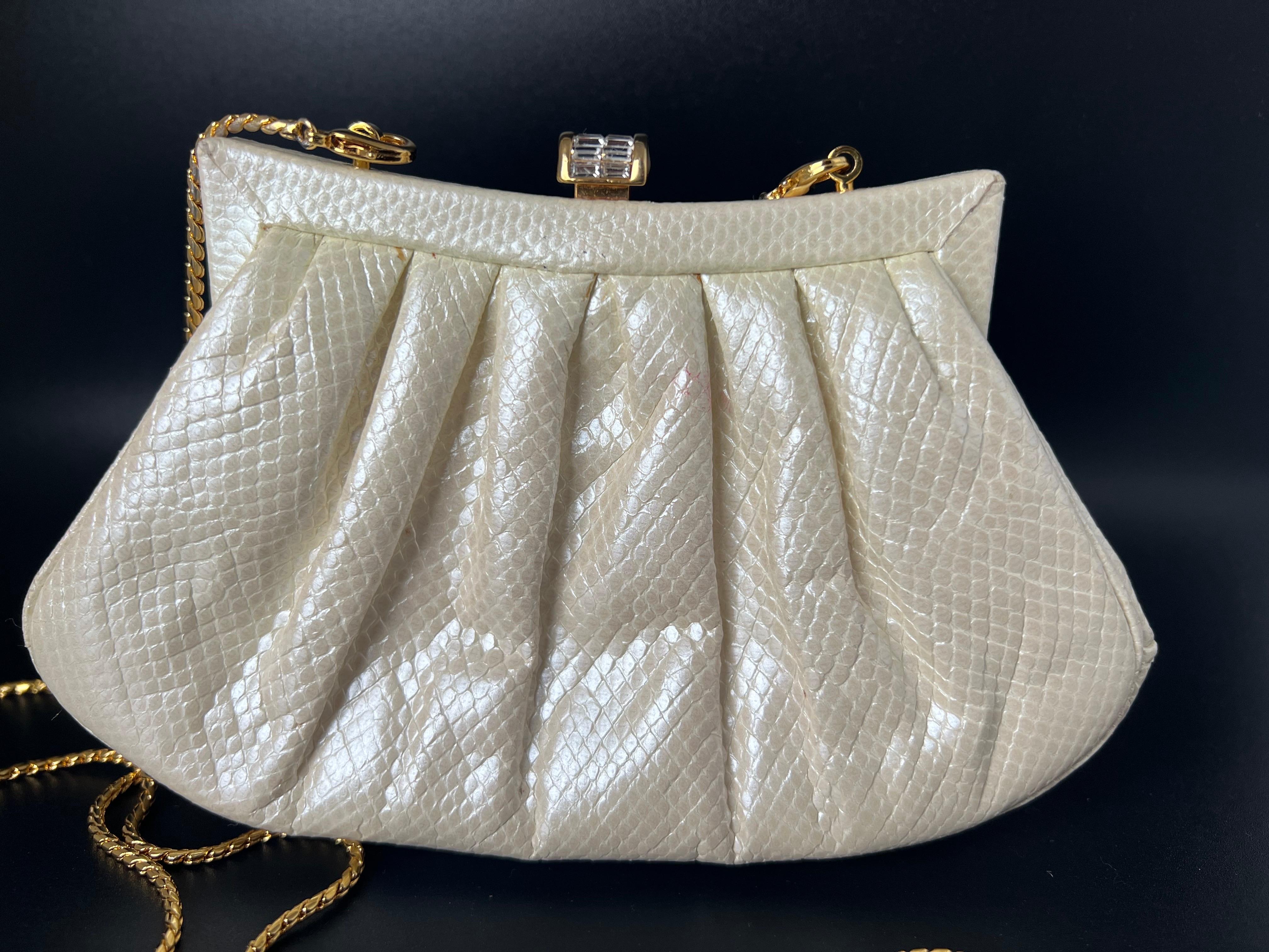 This Judith Leiber clutch exudes timeless sophistication and elegance. Crafted from luxurious ivory or cream white lizard snakeskin-like leather, the bag showcases Leiber's meticulous attention to detail. The pleated design lends an air of
