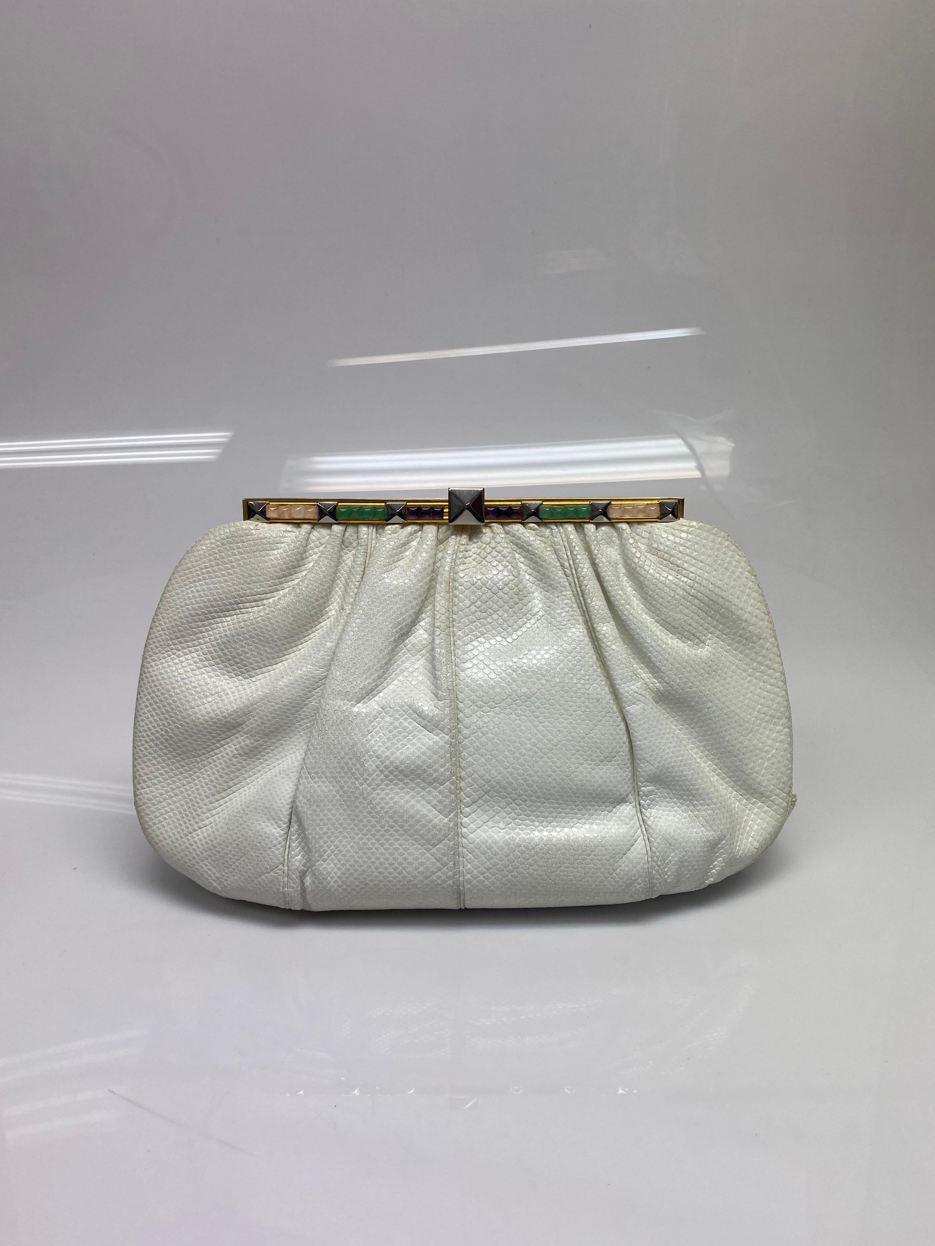 Judith Leiber Ivory Karung Snake Jeweled Clutch. This beautiful vintage bag by Judith Leiber is the perfect addition to any outfit. The bag features gold hardware with a jewel closure. The bag also has loops on each side where you can slide in a