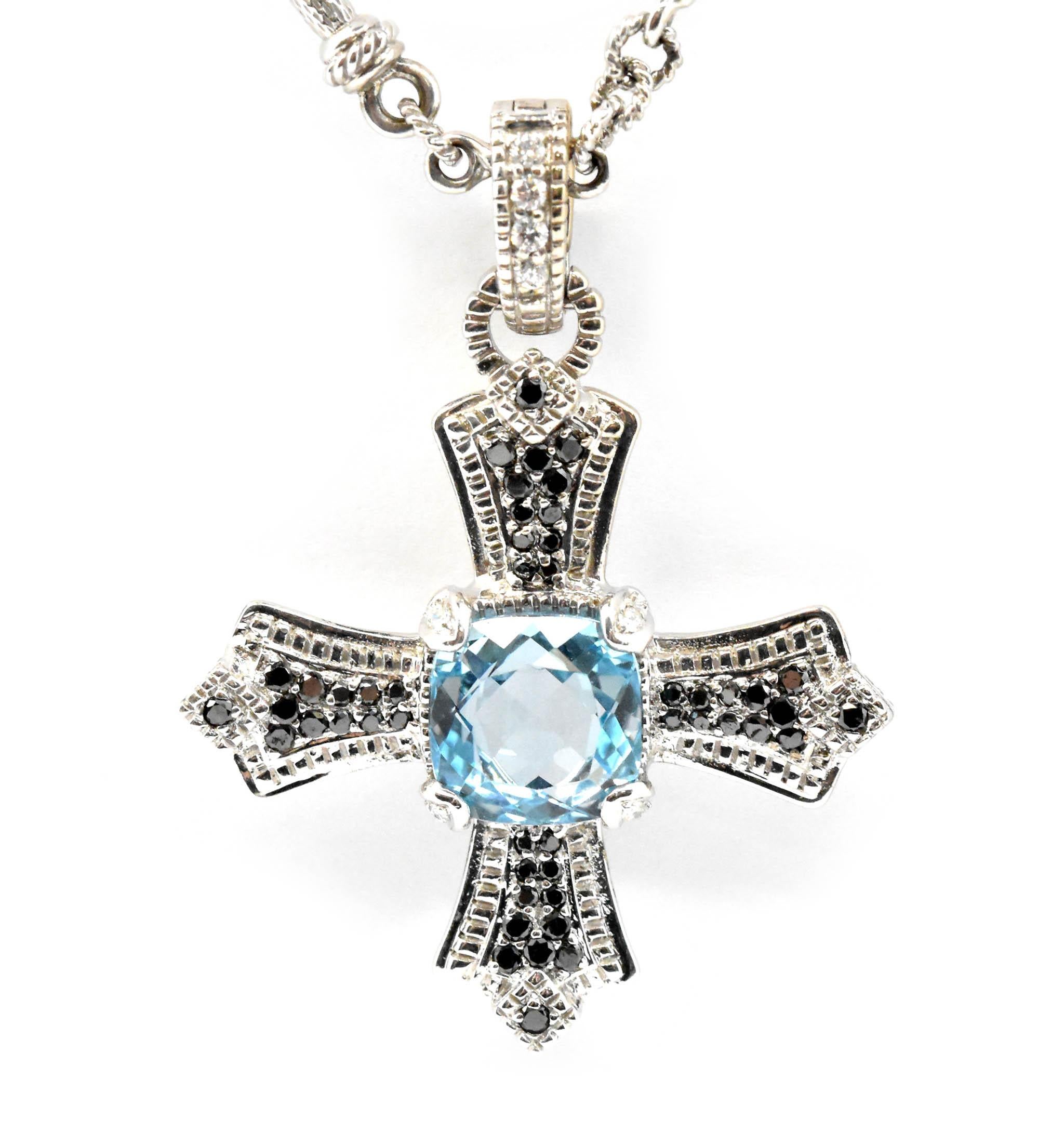 This cross and chain necklace is made in 18k white gold by Judith Ripka. The cross features a 9x9mm square cushion cut stunning blue aquamarine at the center and accented with black diamond melee. There are white diamonds in the bail and chain