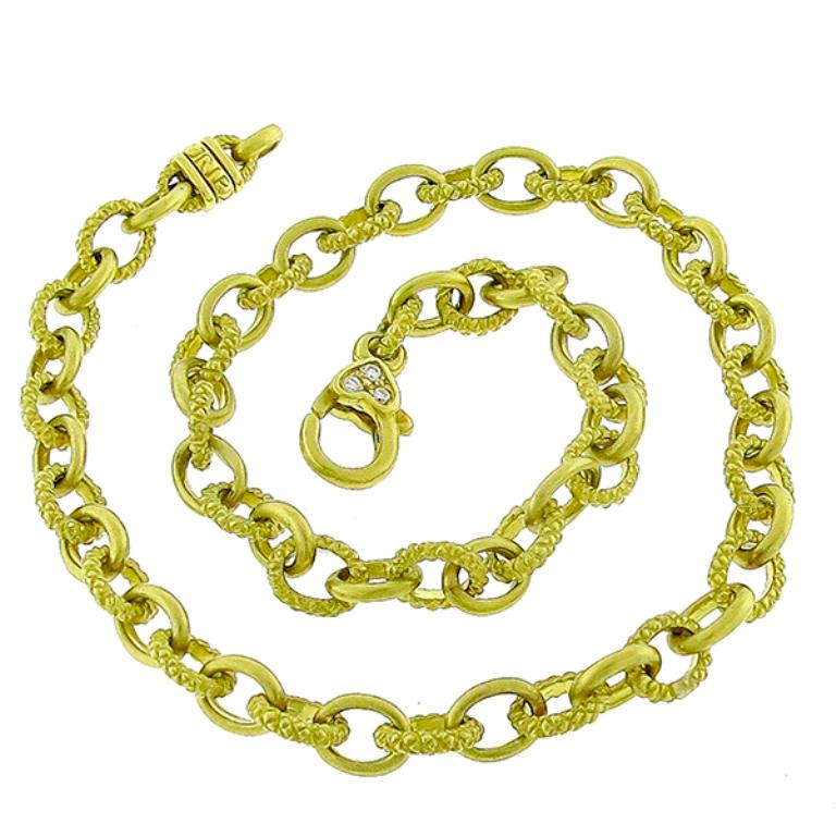 This is a charming diamond 18k yellow gold cable chain by Judith Ripka. The necklace's lobster lock is set with sparkling round cut diamond accent. The necklace feature an alternating smooth and higly textured scale like motif gold cable chain. It
