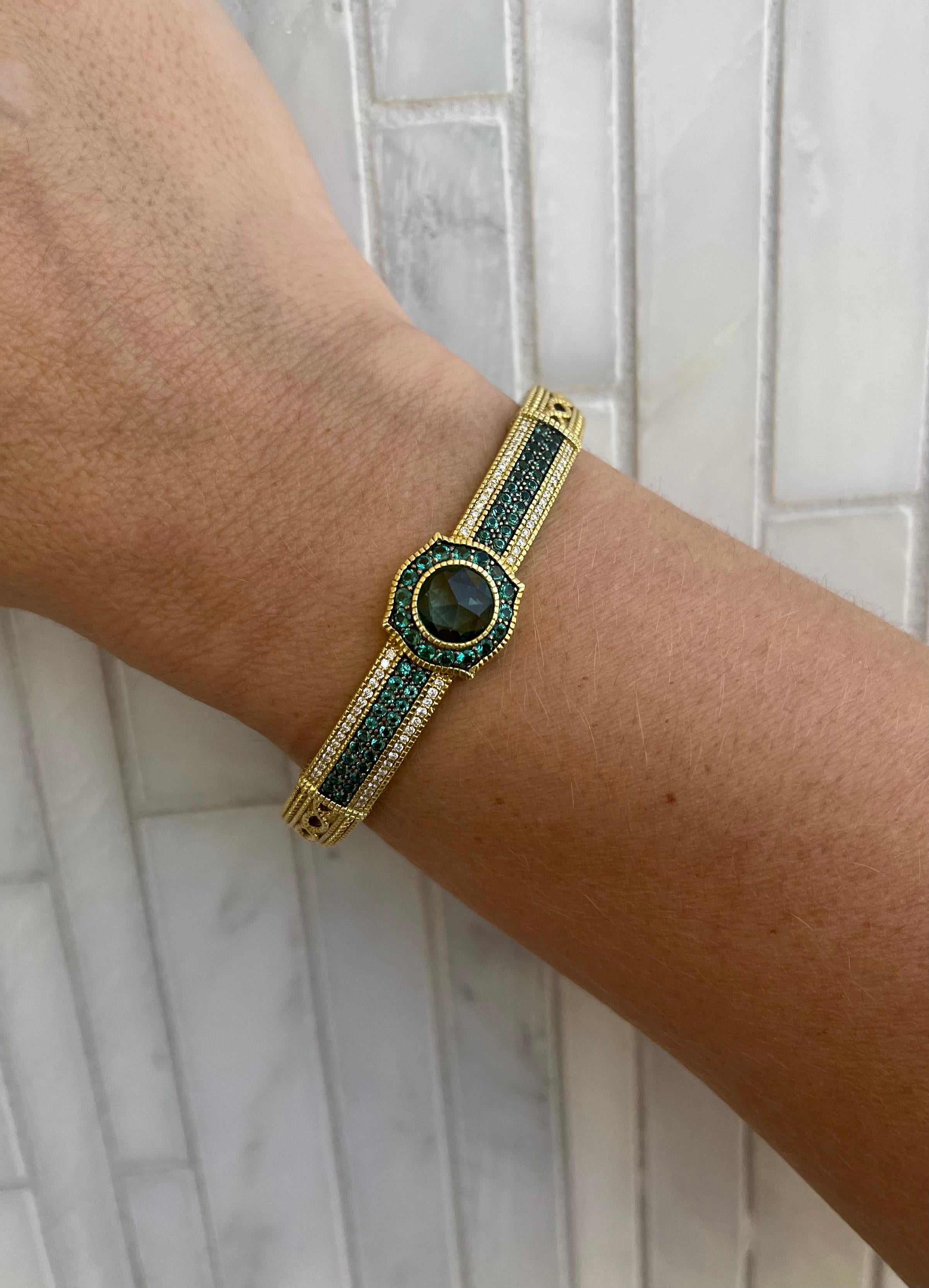 Elevate your style with the exquisite Judith Ripka Green Sapphire Bangle, a true masterpiece of elegance and luxury. Crafted in radiant 18K yellow gold, this bangle exudes timeless charm and sophistication. The star of the show is the stunning 3.5