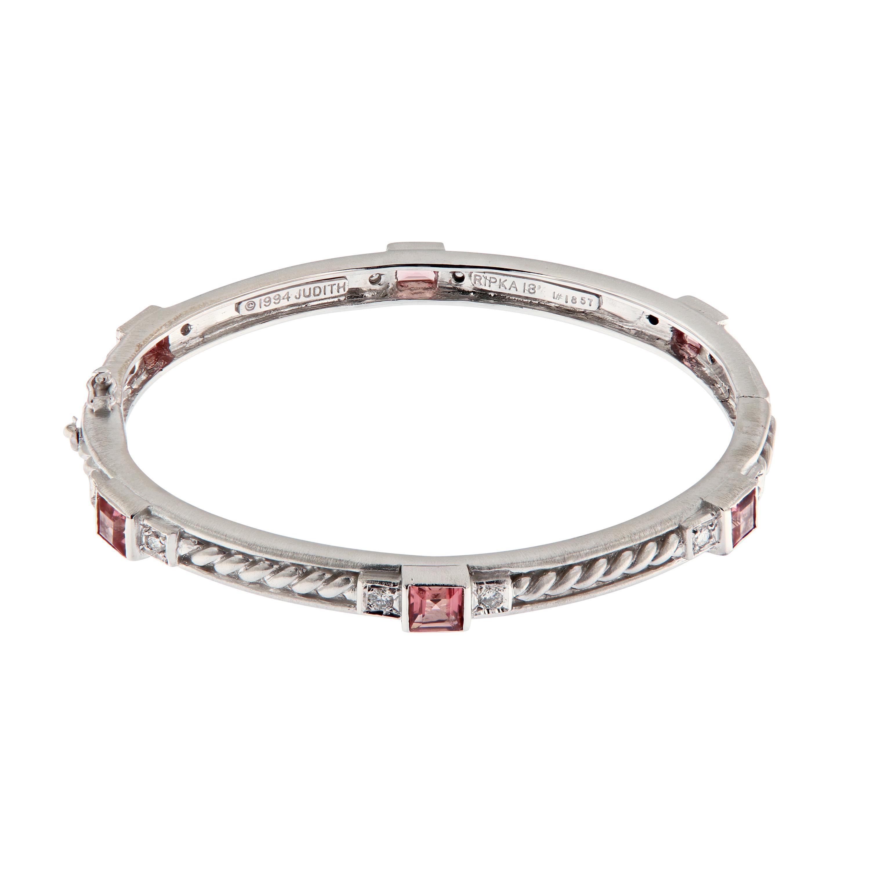 Exquisitely crafted by Judith Ripka in 18k white gold. This bangle bracelet is oval in shape and features a rope design accented with pink tourmalines and white diamonds. This Estate piece is in excellent condition and comes with the original pouch.
