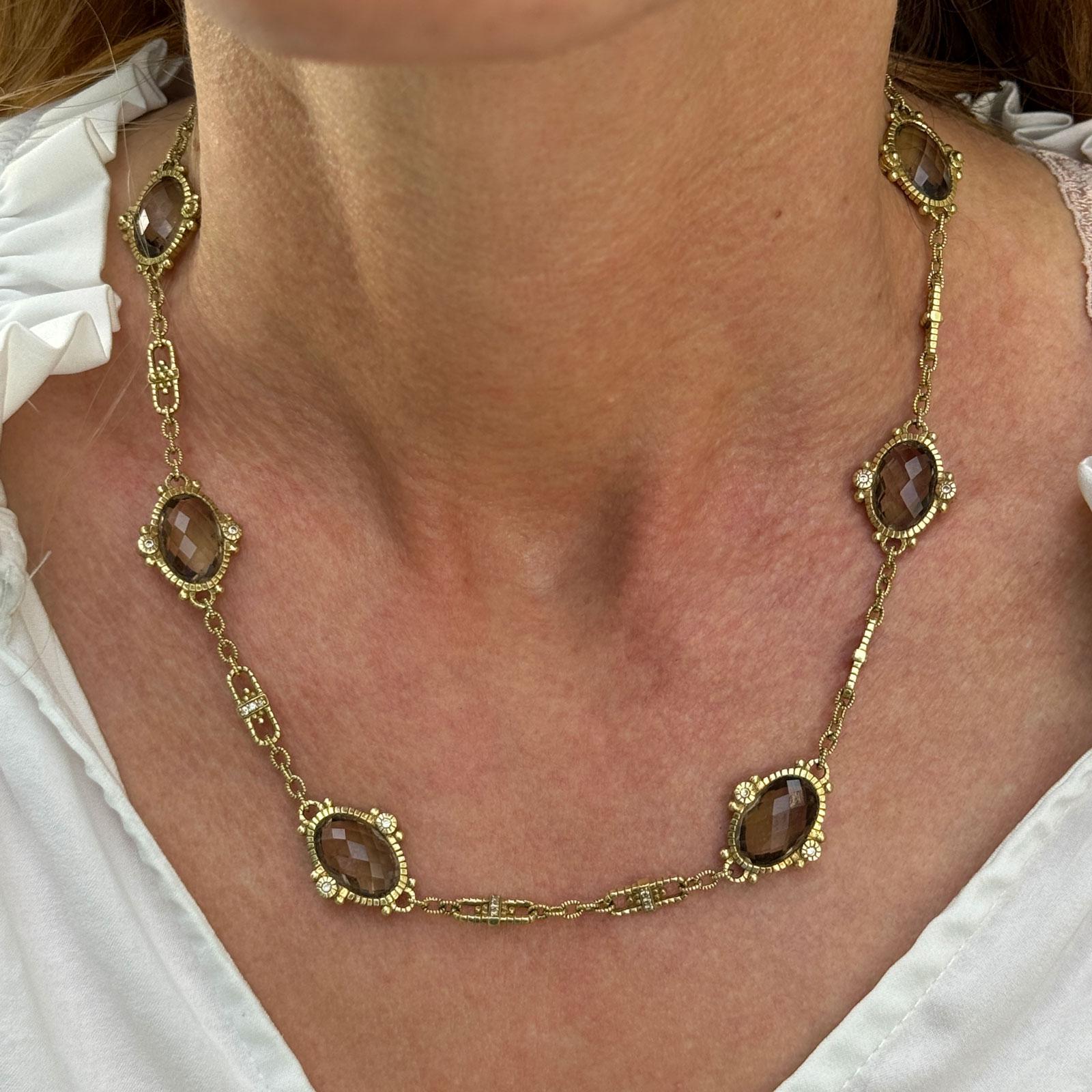 The Judith Ripka Link Necklace is a luxurious and sophisticated piece of jewelry featuring bold 18-karat yellow gold links, meticulously crafted for a timeless yet modern look. Adorned with oval shape smoky quartz gemstones, the necklace offers a