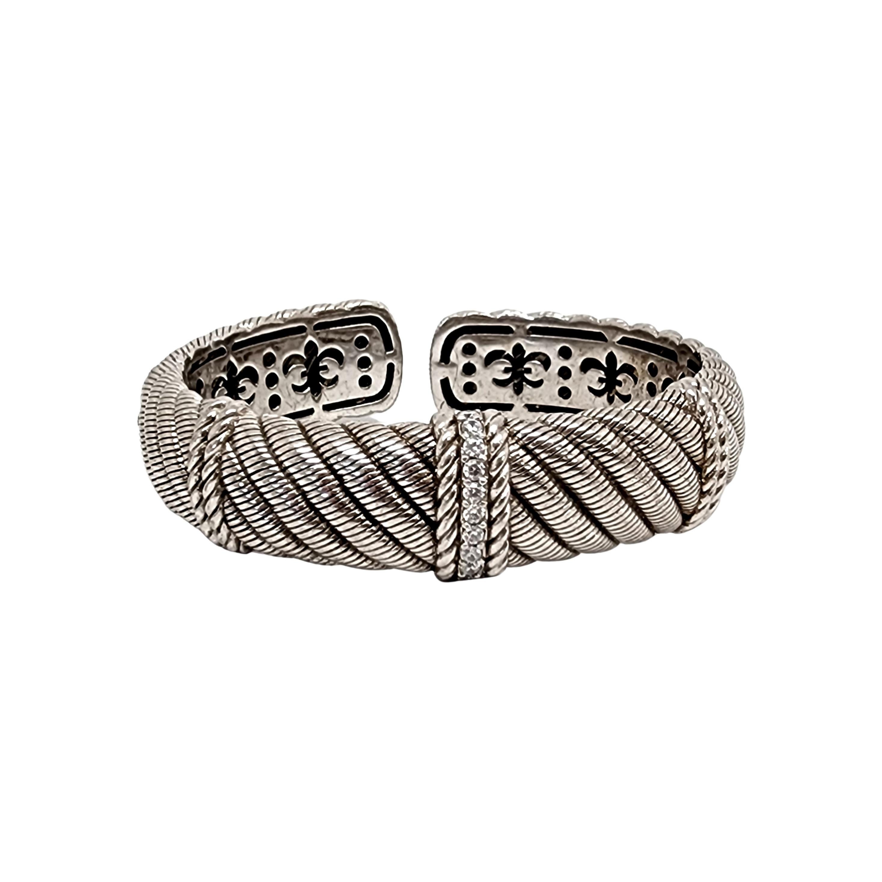 Sterling silver and CZ Diamonique wide cable twist hinged cuff bracelet by Judith Ripka

Designer piece featuring a hinged opening, diagonal cable design and a row of small round faceted prong-set CZs  at the center.

Measures approx 7
