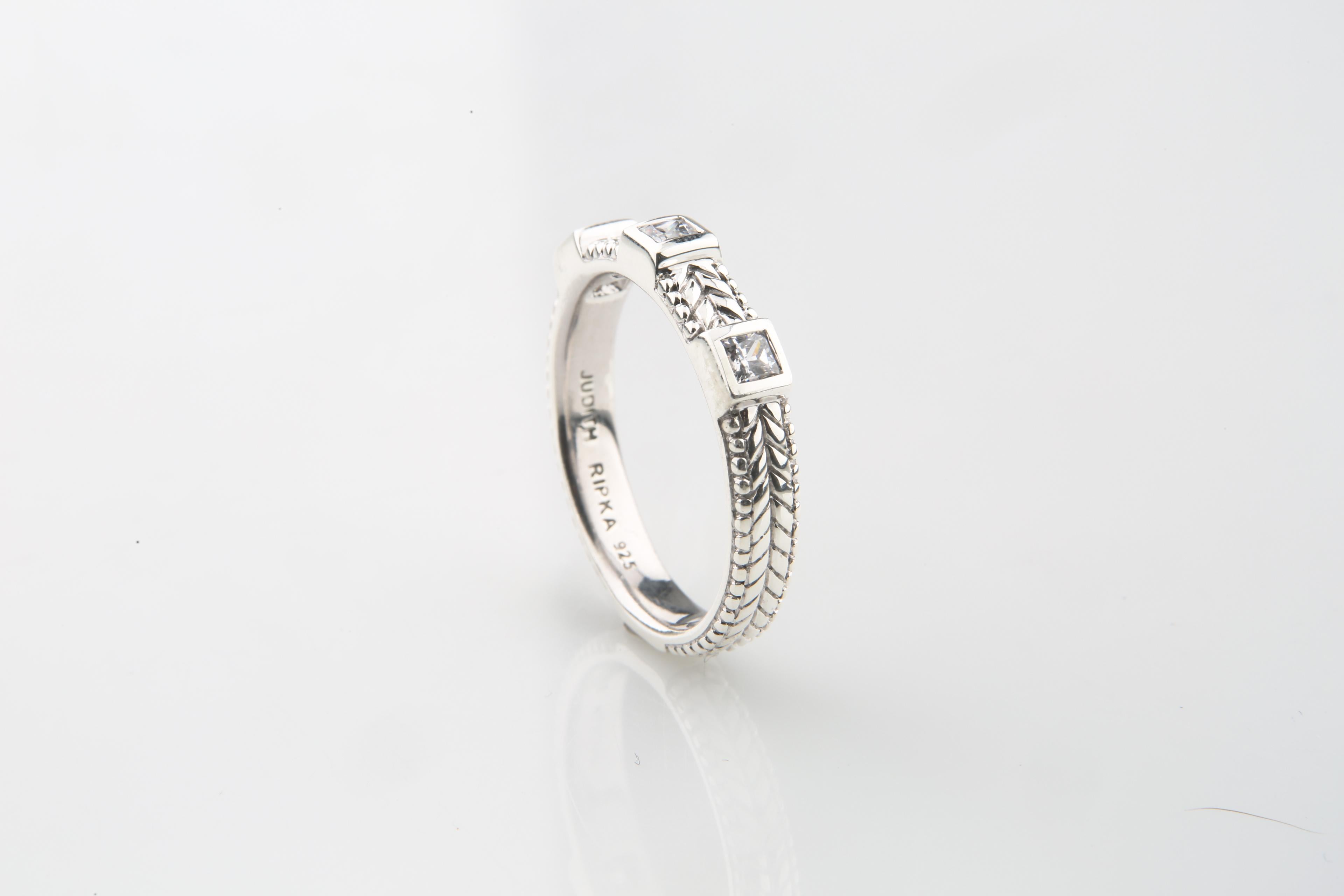 Gorgeous sterling silver & cubic zirconia ring from Judith Ripka.
Textured band ring set with three square-cut cubic zirconia in square settings.

Size 8.75.
3.8 mm wide.
Interior hallmarked with 