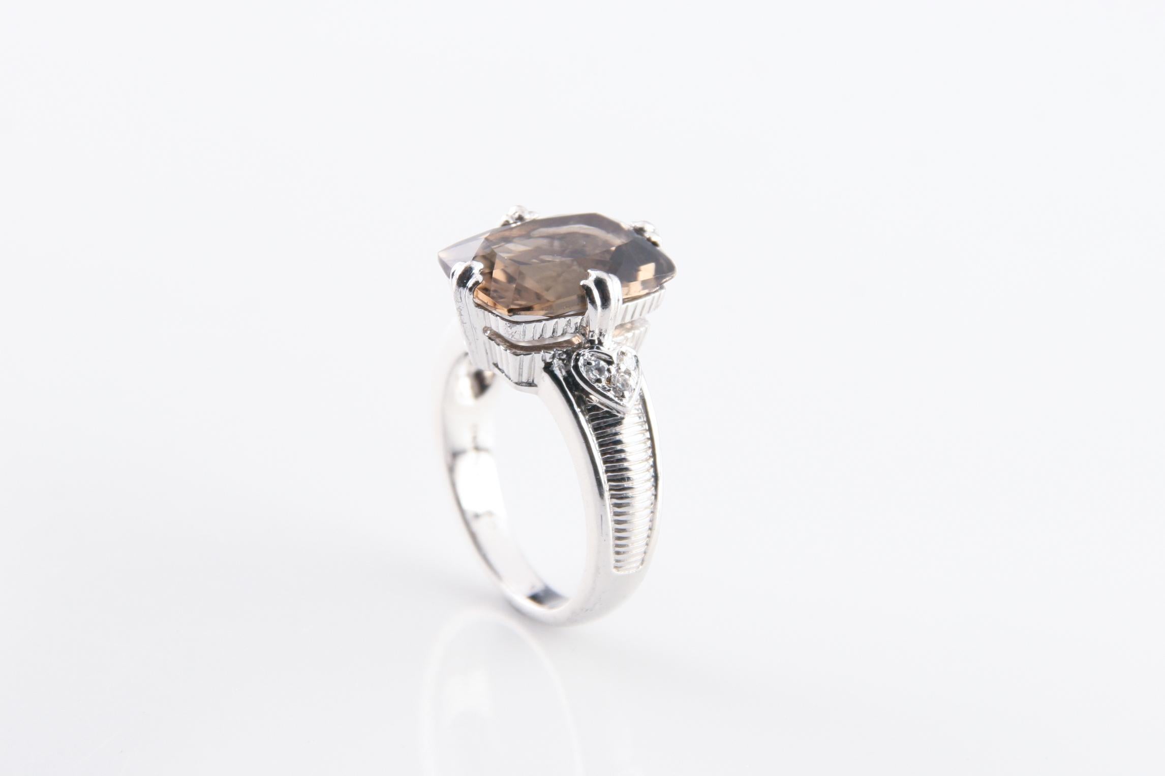 Gorgeous sterling silver solitaire ring featuring a cushion cut smoky quartz with pavé-set cubic zirconia heart accents.
Dimensions of Quartz: 12 mm x 16 mm.
Weight: 10.5 grams.
Size: 10.
Great condition.
An amazing, unique design by the inimitable