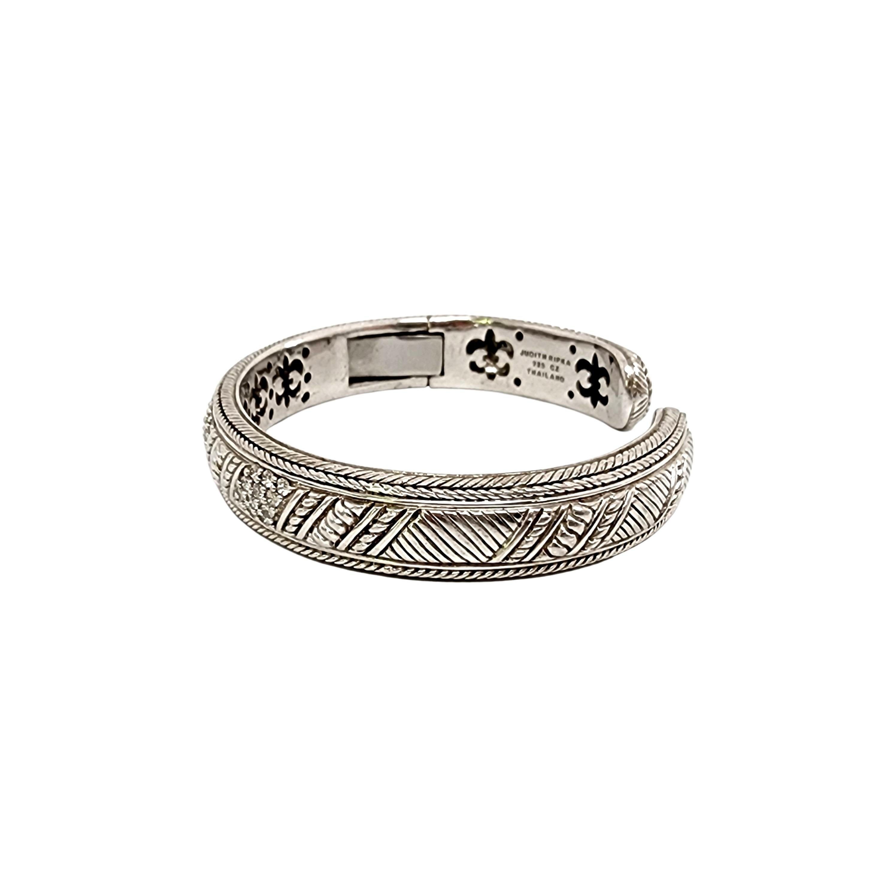 Sterling silver and CZ Diamonique hinged cuff bracelet by Judith Ripka

Designer piece featuring a hinged opening, diagonal row clusters of small round faceted prong-set CZs with textured accents around the cuff.

Measures approx 7 1/4