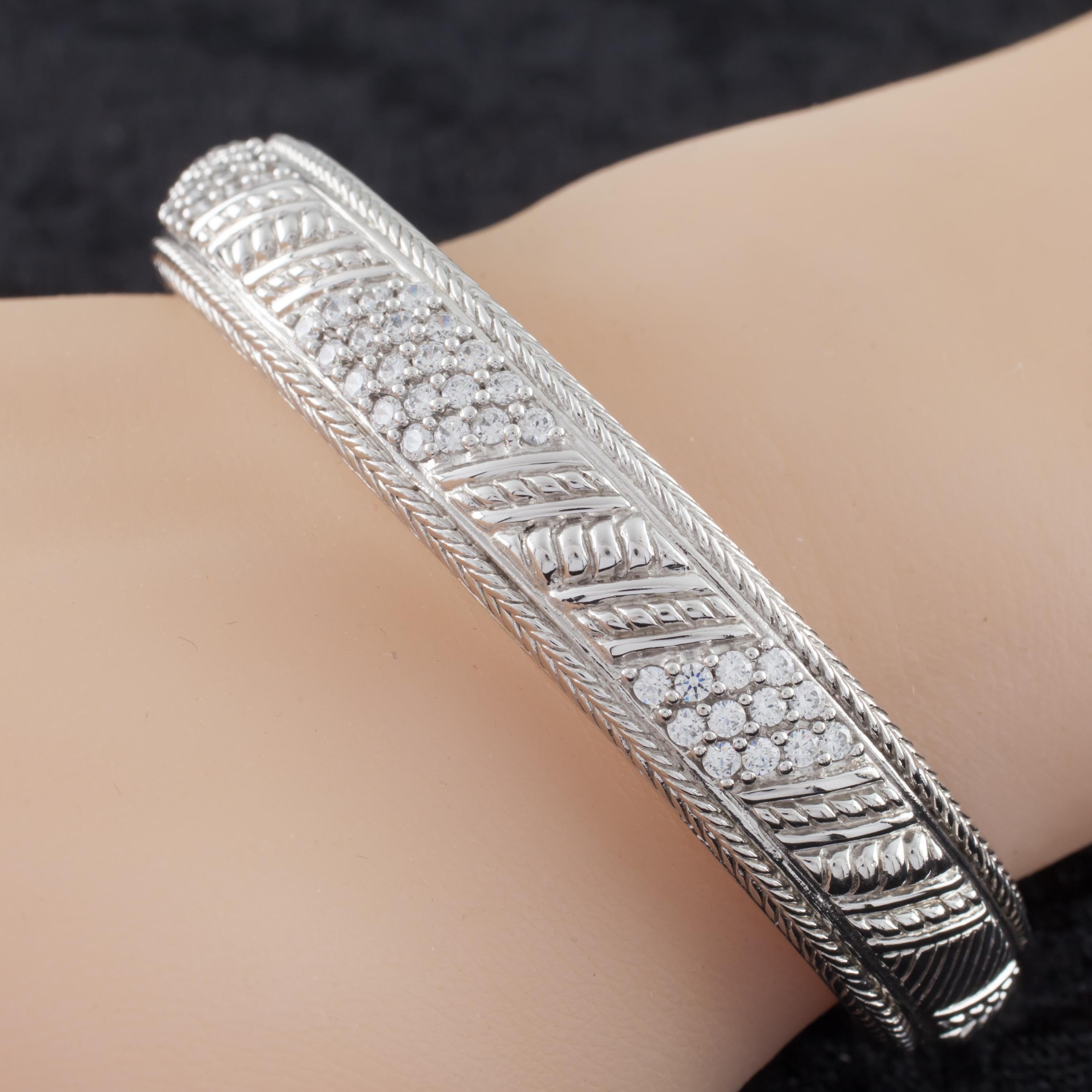 Gorgeous sterling silver cuff bracelet by Judith Ripka.
Features diagonal rows of pave-Set cubic zirconia in a textured sterling silver cuff.
Piece is in good condition and shows few signs of aging or wear.
Wrist Fit: 6.5 inches.
Width: 12