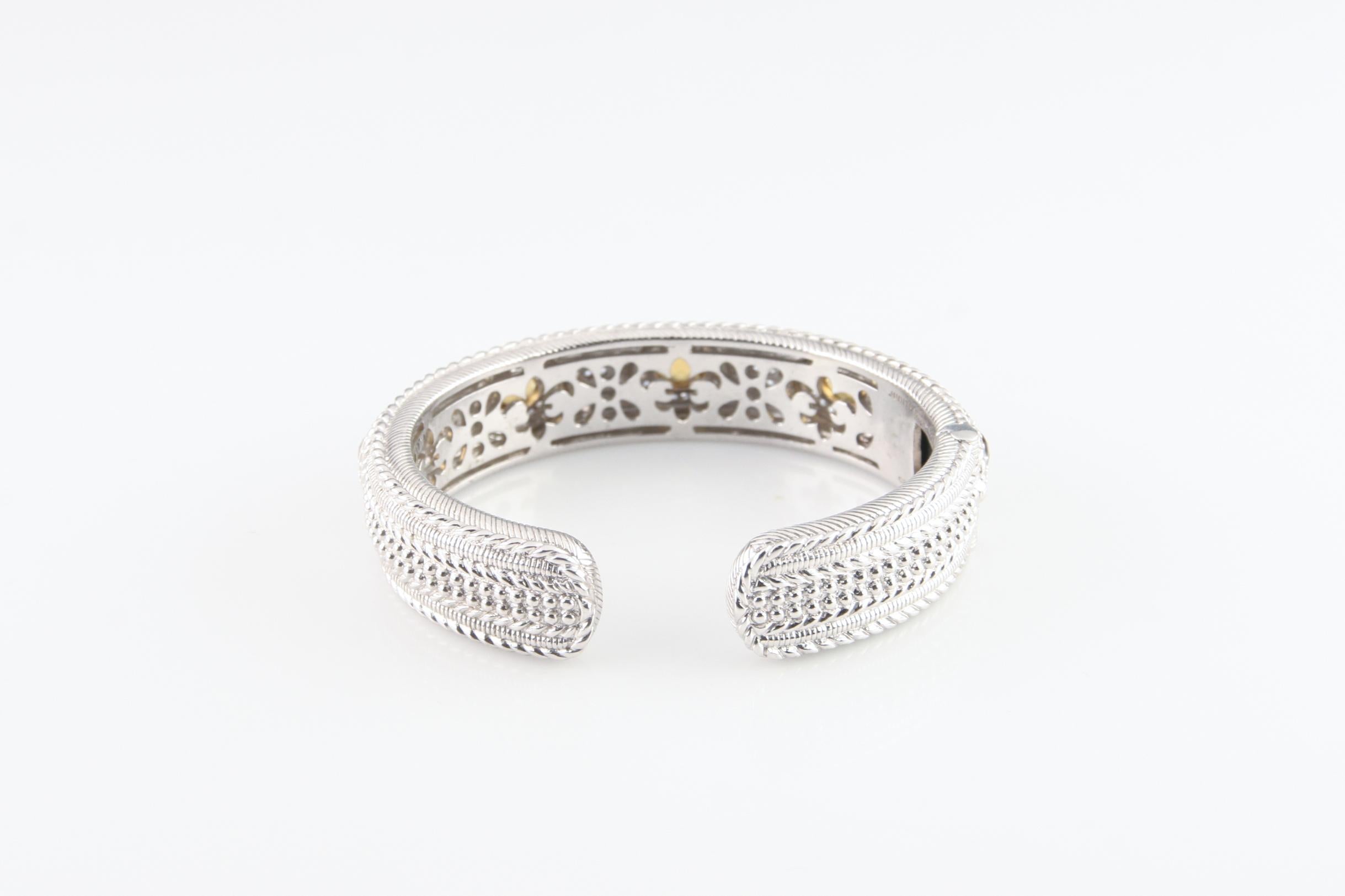 Splendido bracciale a cerniera grande di Judith Ripka.
Con cinque quarzi cognac tagliati a cuscino, ognuno dei quali è incastonato con un castone e due file di zirconi (diamonique).
Circonferenza interna (adattamento al polso): 7