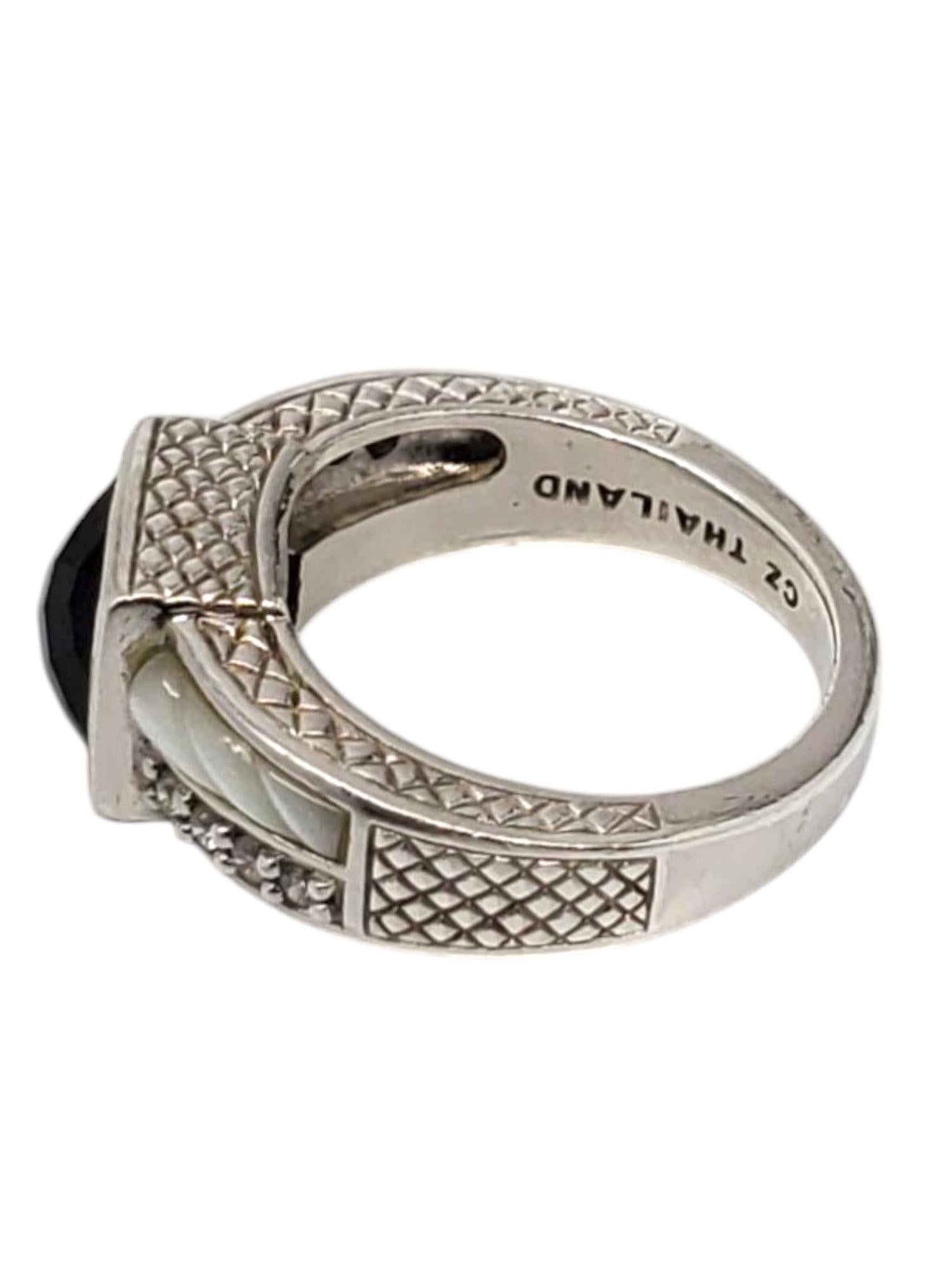 Judith Ripka Sterling Silver Onyx Mother Of Pearl and  CZ Ring -

This lovely ring by Judith Ripka features a square faceted onyx (7.7 mm x 7 mm) with CZ & inlaid mother of pearl accents set in classic sterling silver

Shank: 3 mm

Front of ring