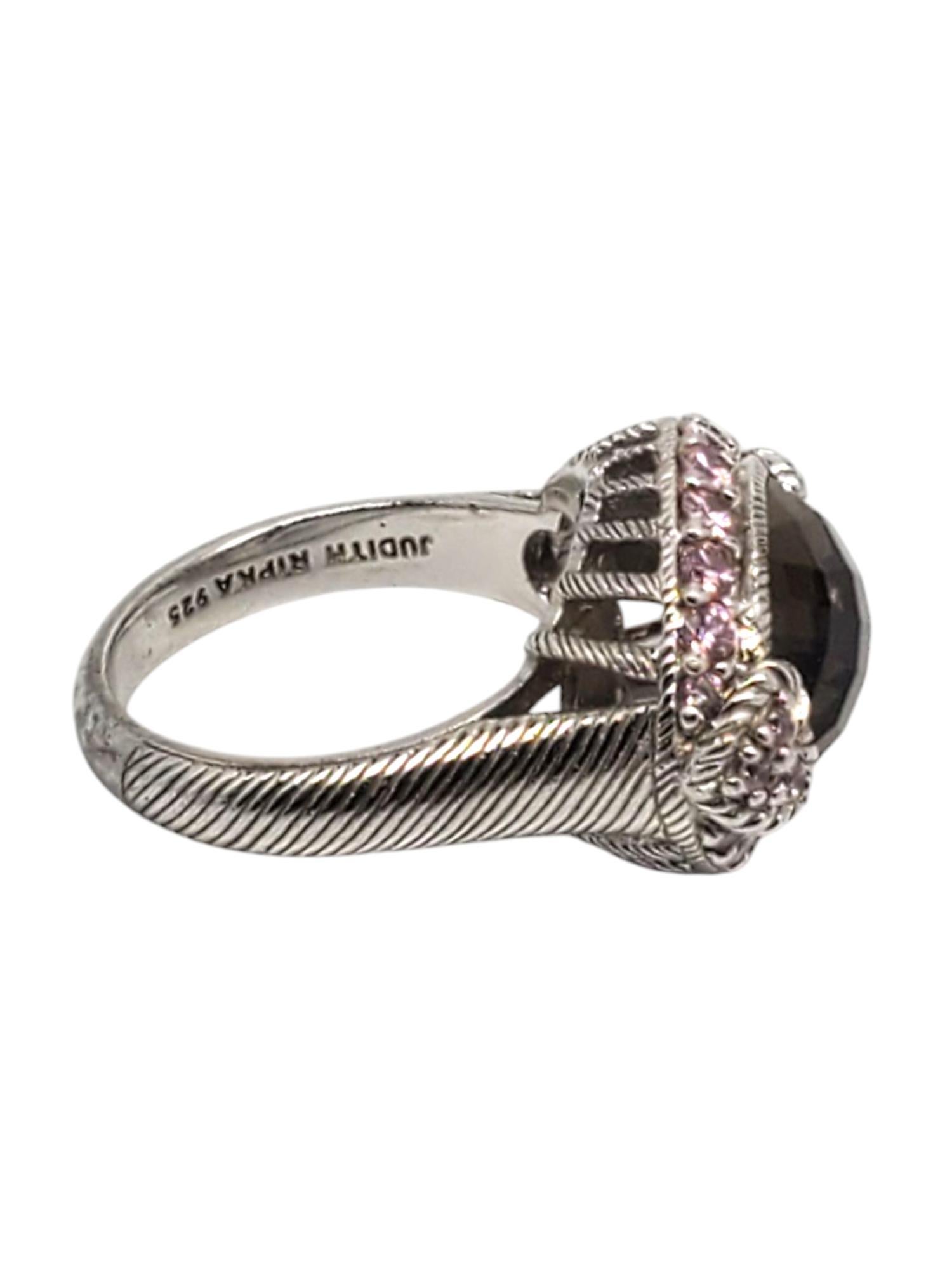 Judith Ripka Sterling Silver Smoky Quartz & Pink CZ Ring 

This elegant ring features a large faceted oval smoky quartz(11.6 mm x 9.6 mm) surrounded by pink CZ set in sterling silver textured design by Judith Ripka.

Shank: 3 mm

Front of ring