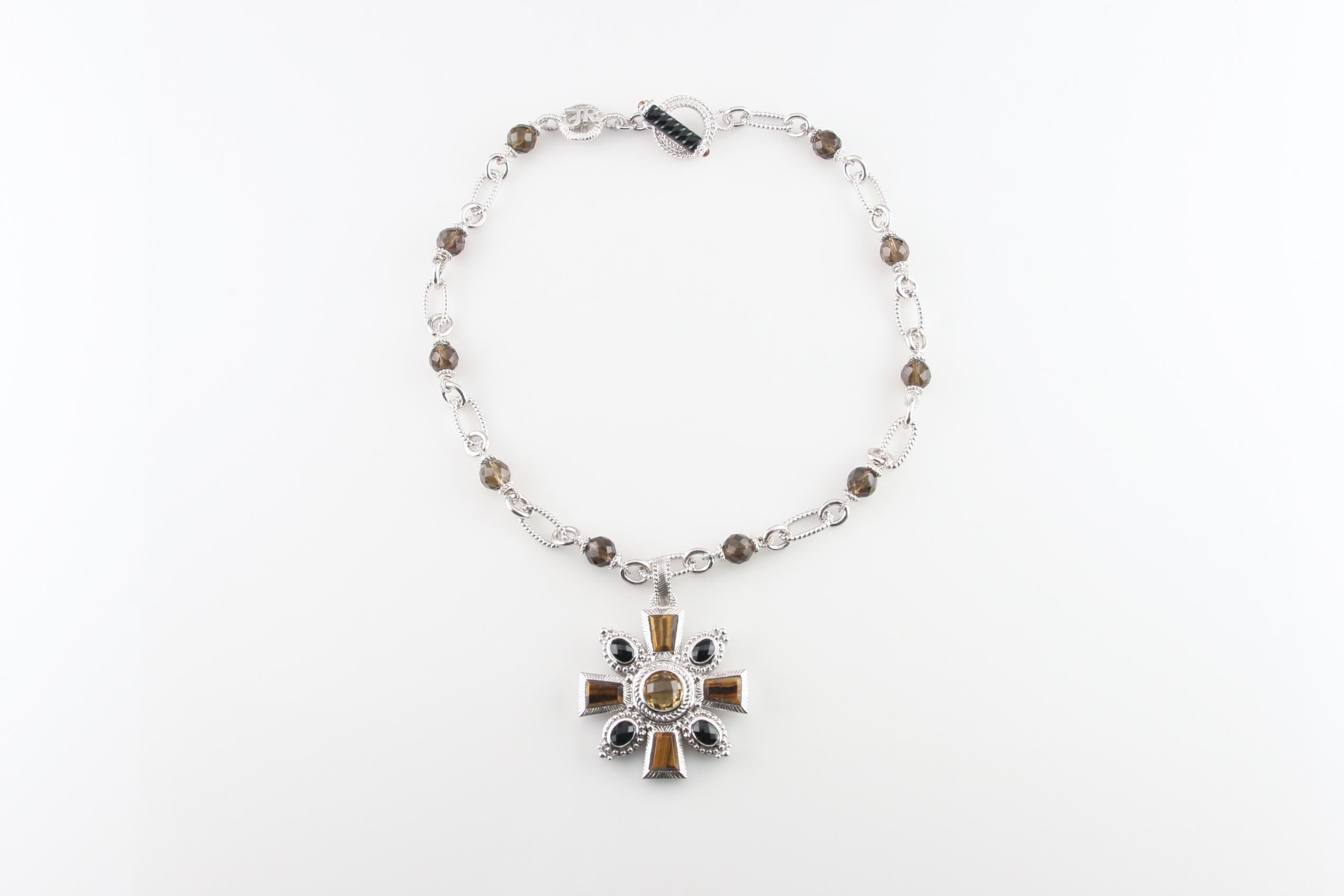Splendida collana a catena in argento sterling di Judith Ripka con un esclusivo ciondolo a forma di croce di Malta.

Il ciondolo presenta un occhio di tigre tagliato su misura, un'onice tagliata a cuscino e un citrino tagliato a cuscino.
Lunghezza
