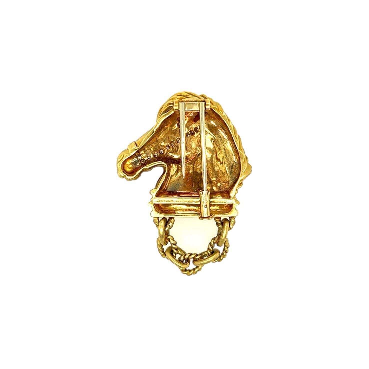 An 18 karat yellow gold and diamond brooch, Judith Ripka.  Fashioned as a matte gold horse head in profile, the bridle set with twenty two brilliant cut diamonds, suspending a short length of chain. Total diamond weight approximately 0.40 carat. 