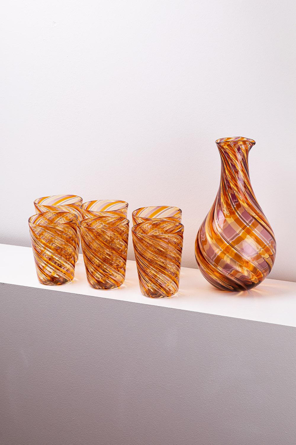 Questo set di sette pezzi, tra cui una brocca e sei bicchieri, è uno straordinario esempio di artigianato italiano del vetro di Murano, che fonde il design moderno con le tecniche tradizionali. Disegnato da Mariana Iskra, questo set è caratterizzato