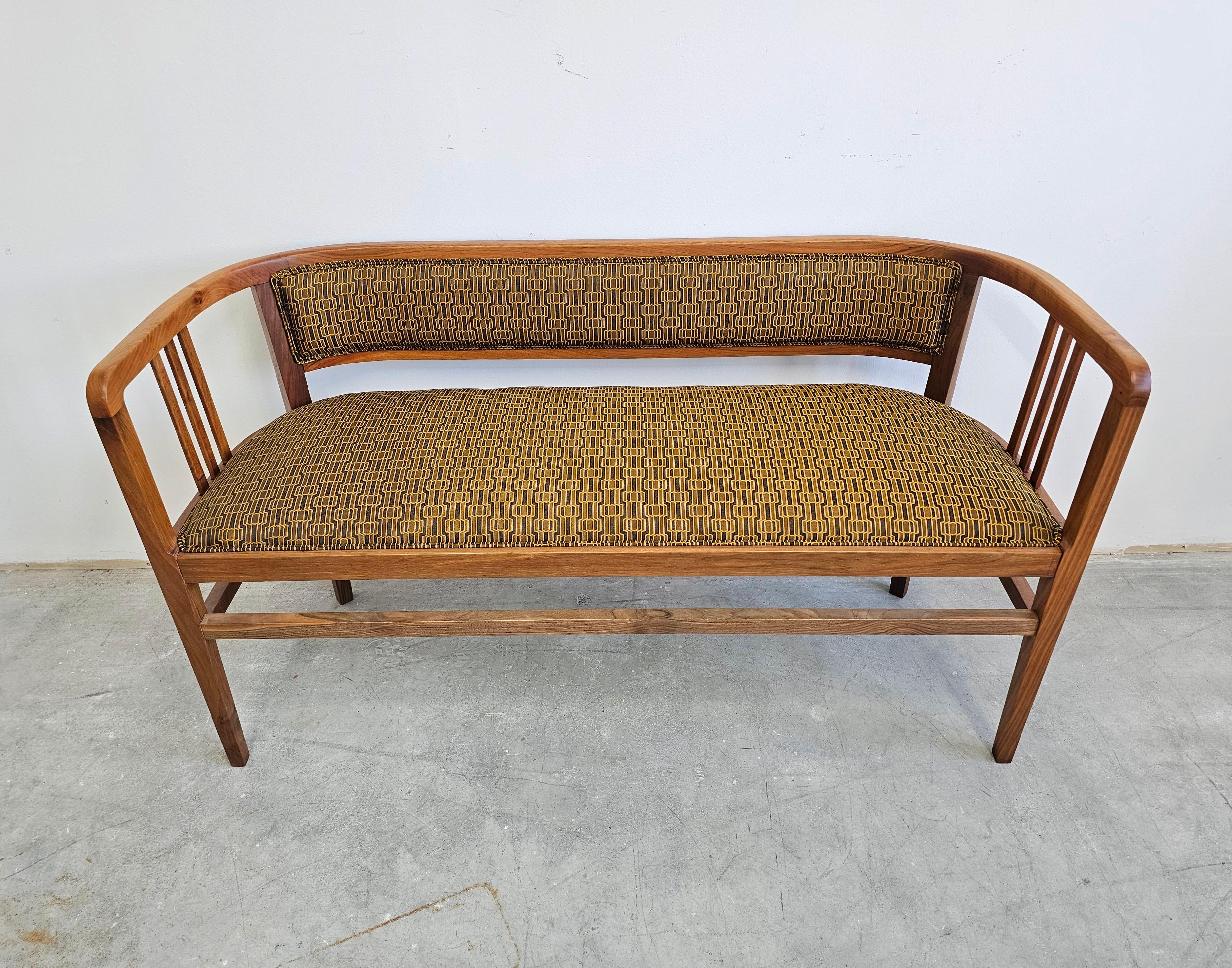 Dans cette annonce, vous trouverez une magnifique et chaleureuse banquette ou un canapé Jugendstil conçu dans le style d'Otto Wagner. Elle est réalisée en noyer massif et recouverte d'un tissu à motif géométrique noir, or et bronze. Fabriqué en