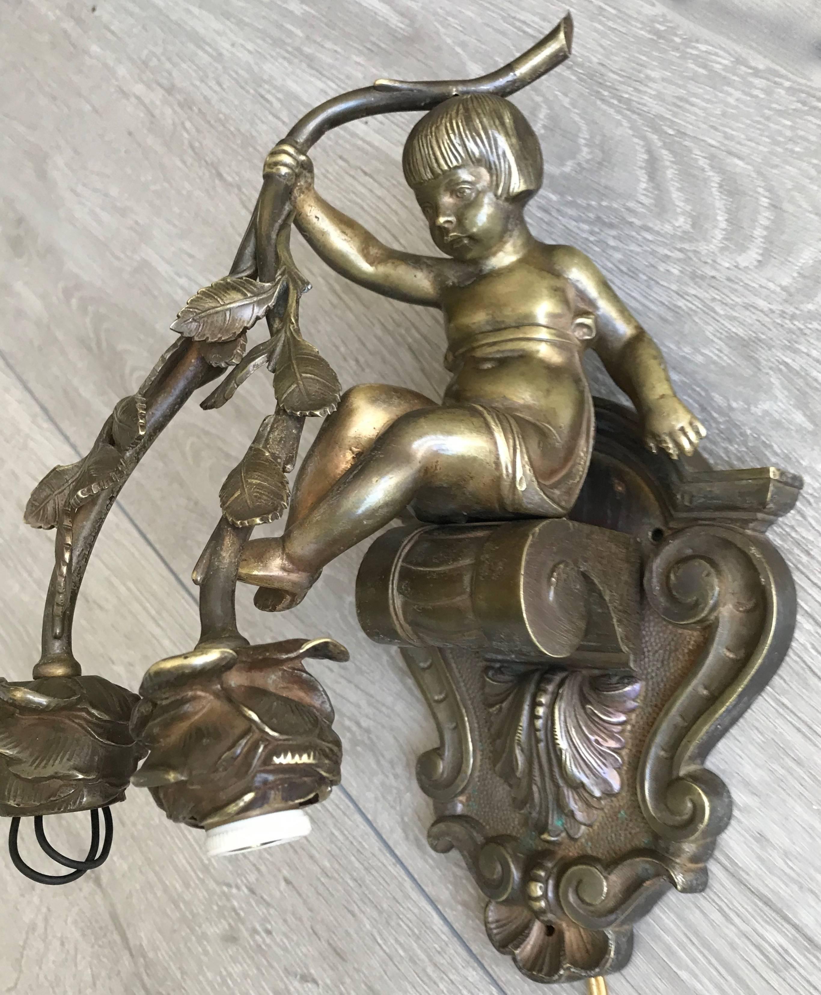 Rare and original bronze wall bracket sconce.

If children and flowers bring joy to your life then this antique wall sconce could be perfect for you. This sculptural bronze wall light depicts a boy sitting on a neoclassical bracket whilst holding up