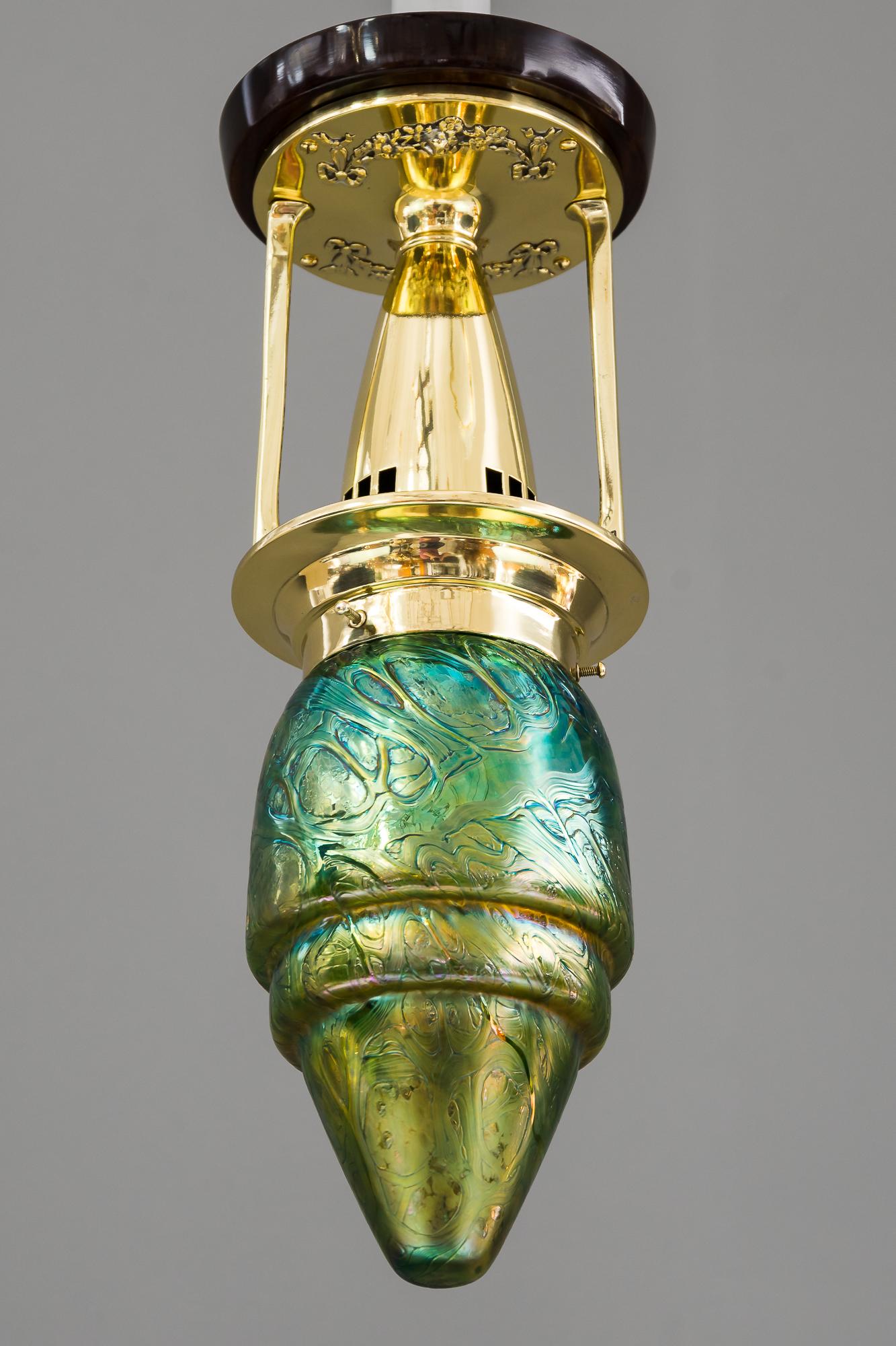 Jugendstil ceiling lamp, Vienna, circa 1908.
Brass polished and stove enameled
Wood plate on top polished
Glass in loetz style.
  