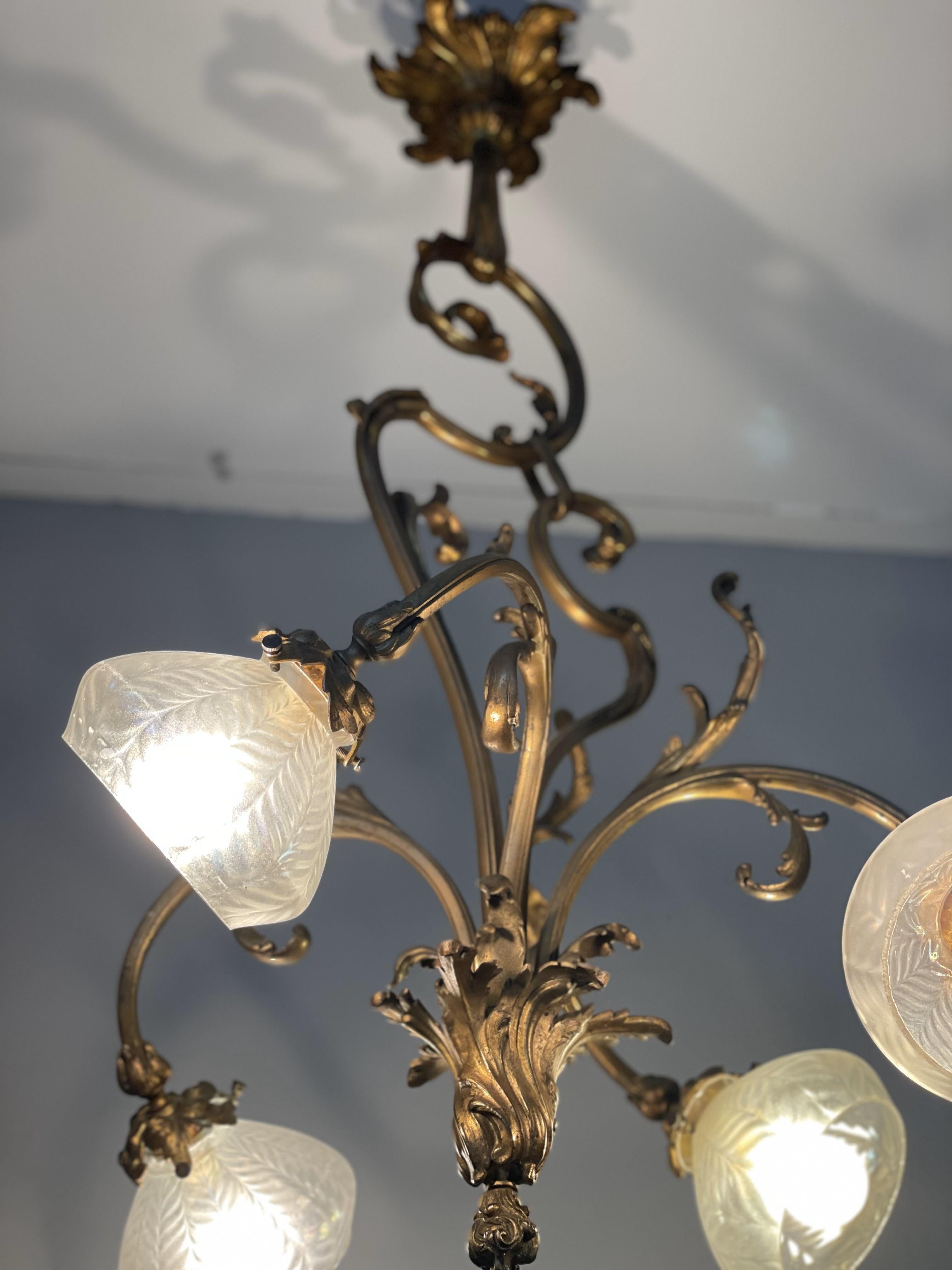 Lustre vintage magnifiquement orné d'un cadre doré aux détails incurvés et de quatre abat-jours en verre dépoli. Son design intemporel ajoute de la sophistication et une touche d'élégance à n'importe quelle pièce.