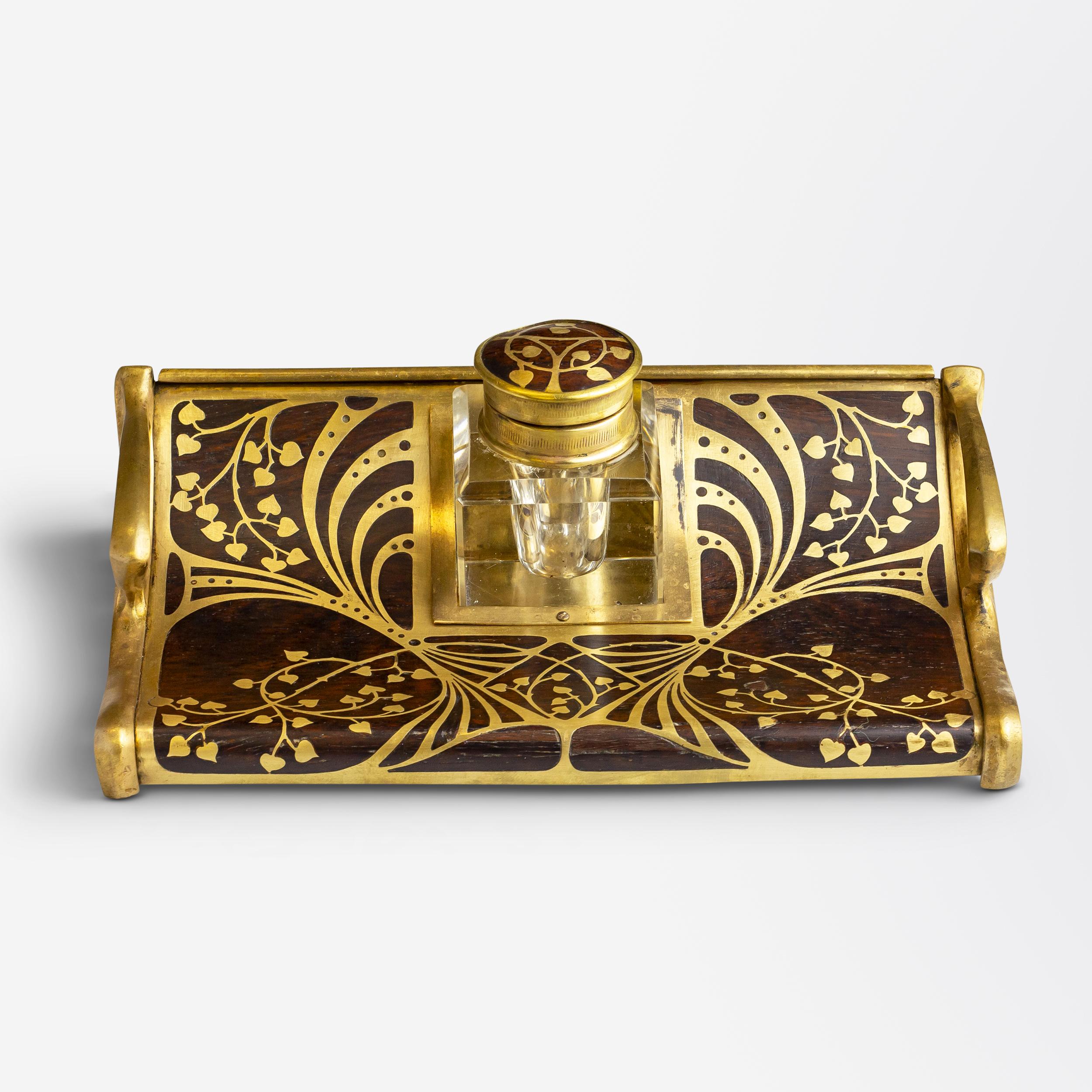 Realizzato in Germania durante l'epoca dell'Art Nouveau, questo calamaio in ottone e palissandro con supporto è attribuito ai produttori Erhard & Söhne. L'ornato supporto in stile 
