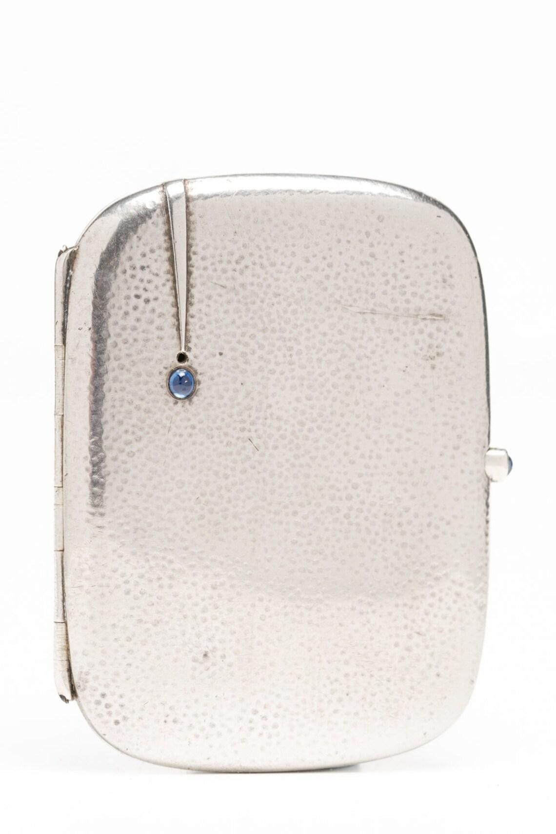 This rare Jugendstil German silver and sapphire cabochon cigarette case was made by renowned German silversmith Louis Kuppenheim, circa 1900. This unique piece is decorated with a geometric line on one side ending with an oval sapphire cabochon