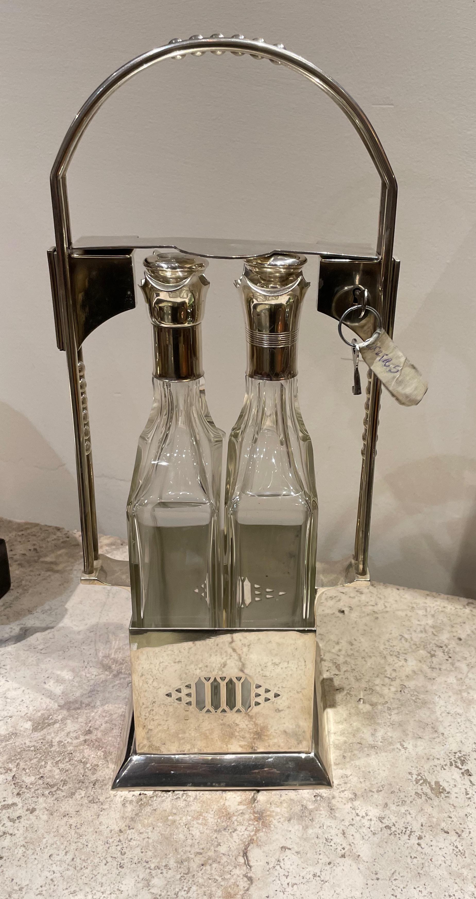 Set à liqueurs vintage Jugendstil Tantalus à deux bouteilles en métal argenté. Cet ensemble élégant a été récemment restauré et se trouve dans un état proche du neuf. La serrure d'origine fonctionne et maintient les deux bouteilles vers le bas pour