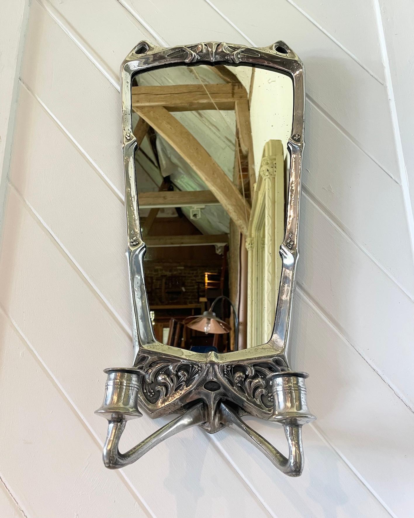 A beautiful wall mirror with double sconce and typical Art Nouveau design work. Design is attributed to Hugo Leven who we know worked in this style. 
Made for Kayserzinn.
The material is Pewter and has been polished. 