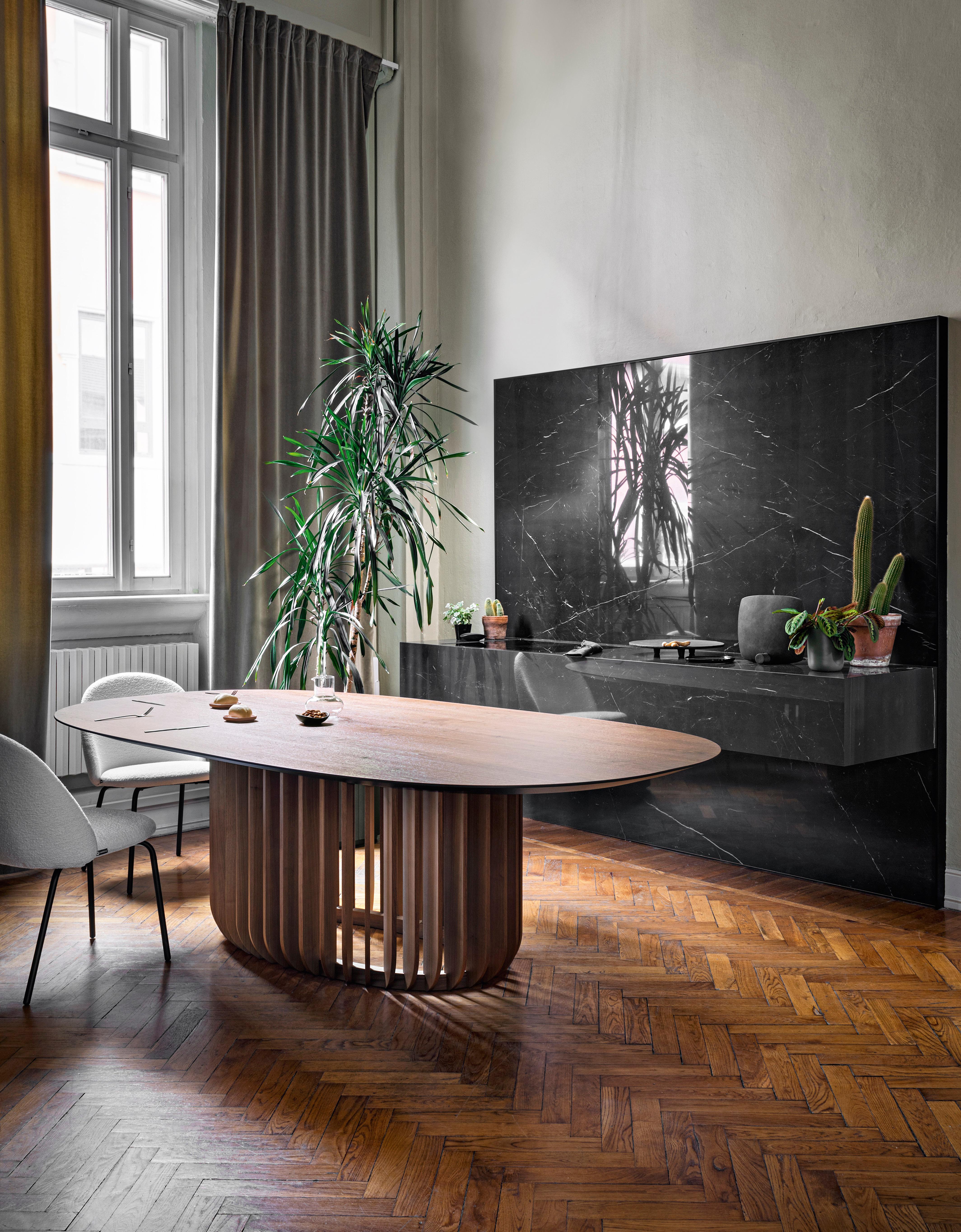 Juice is a monumental table with a meditative air. Its essence lies in the base, where the long wooden legs attach to a ring, encircling it. Juice, a table developed around the balance between filled and empty spaces, creates a sensation of perfect