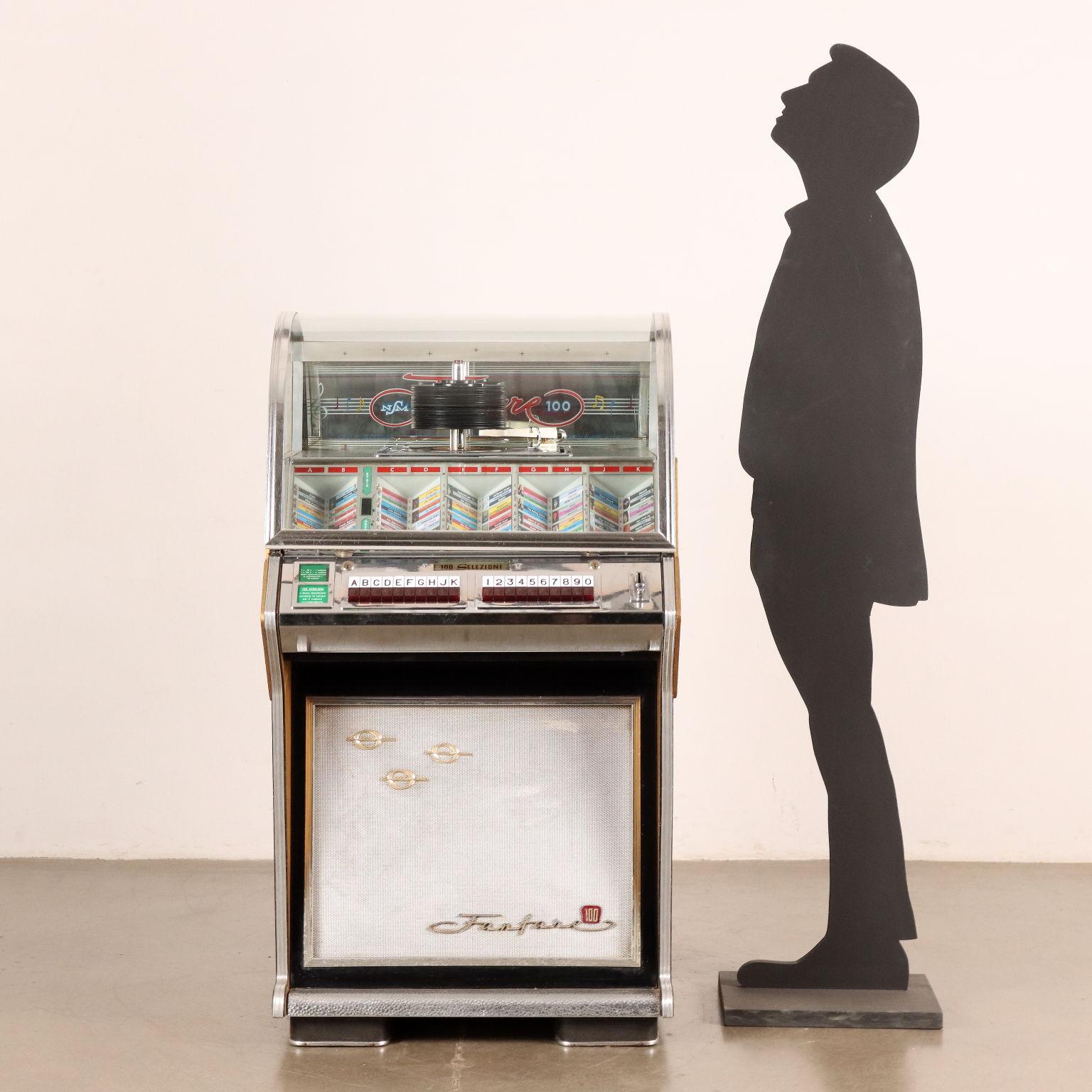 Bellissimo jukebox vintage di fine anni '50 marca NSM modello 'Fanfare 100', revisionato e funzionante. Contiene cento brani musicali tra italiani e internazionali, da 'Vita Spericolata' di Vasco Rossi a 'So Much Trouble' di Bob Marley, passando per