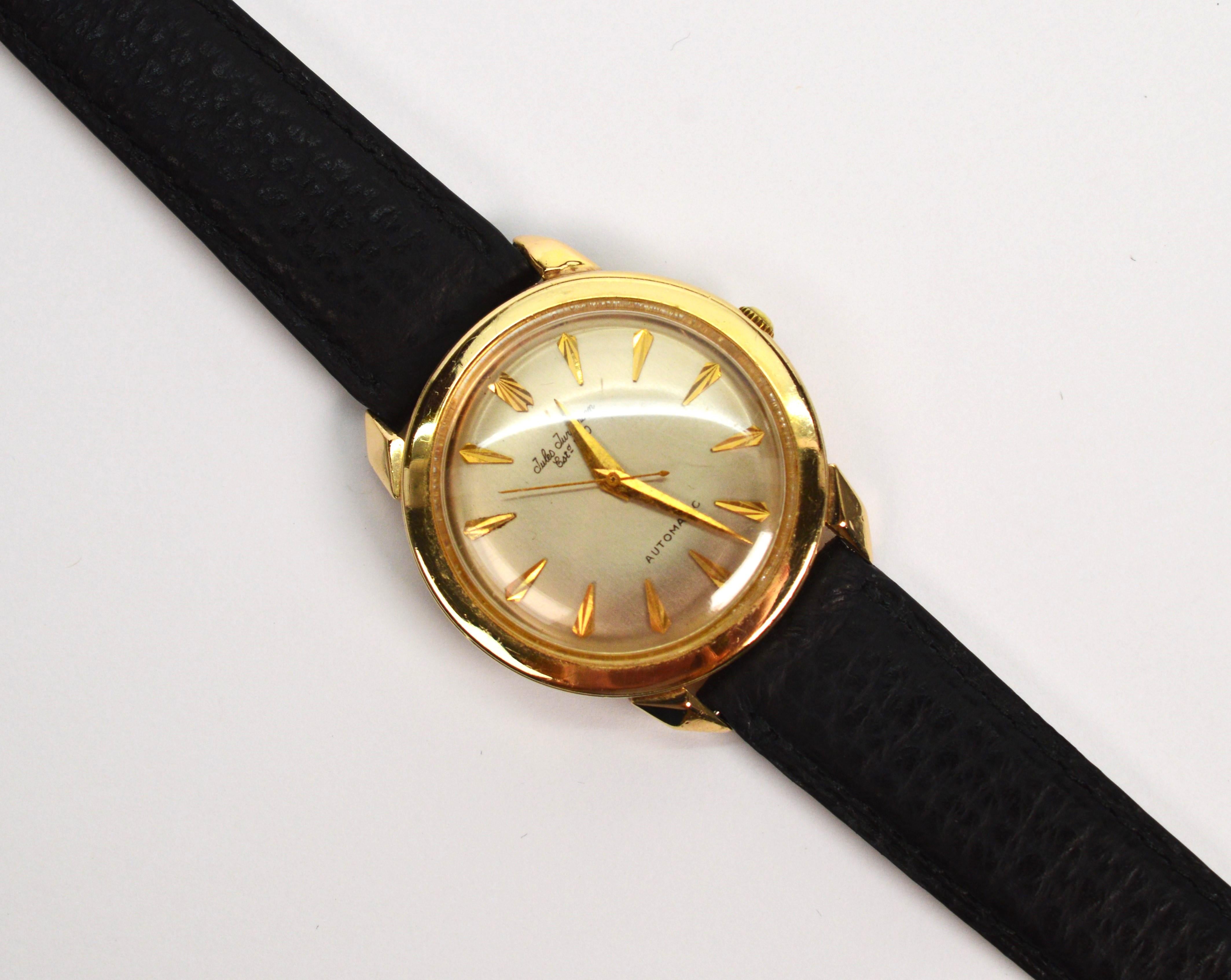 Quintessential 1950's styling by well known Swiss Watch Company, Jules Jurgensen. This 34mm 14 karat yellow gold retro beauty has an automatic 17 jewel movement, serial number 300354. The round case number is 394428 and the dial is silver toned with