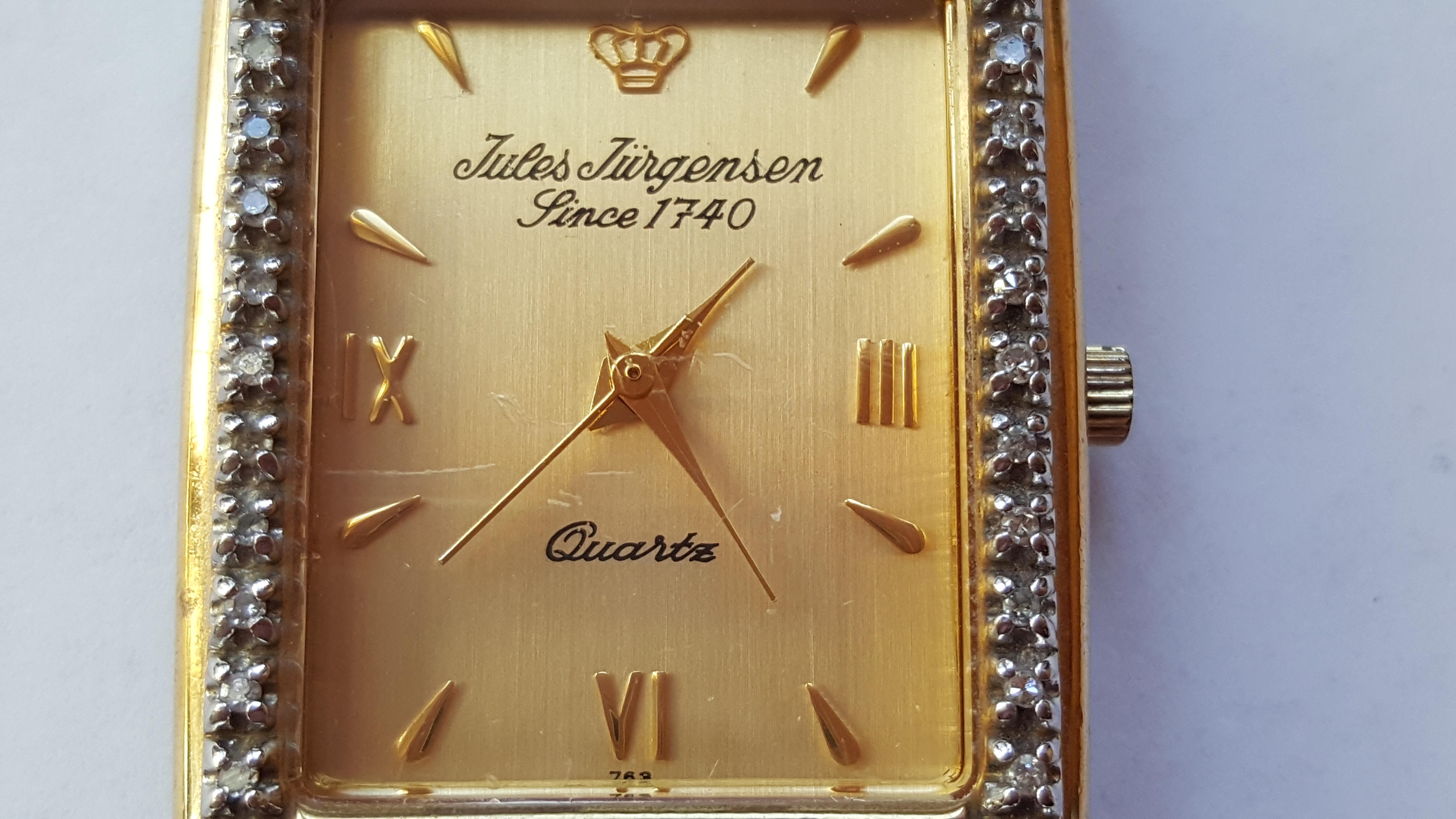 Vintage 1970's (approximately) Jules Jurgensen watch that's stainless steel with a gold-colored plating. Gold face, with diamonds set in white prongs. The case is 26 mm by 36 mm, 7mm thick, 18mm width bracelet that's 3 inches on the long size and