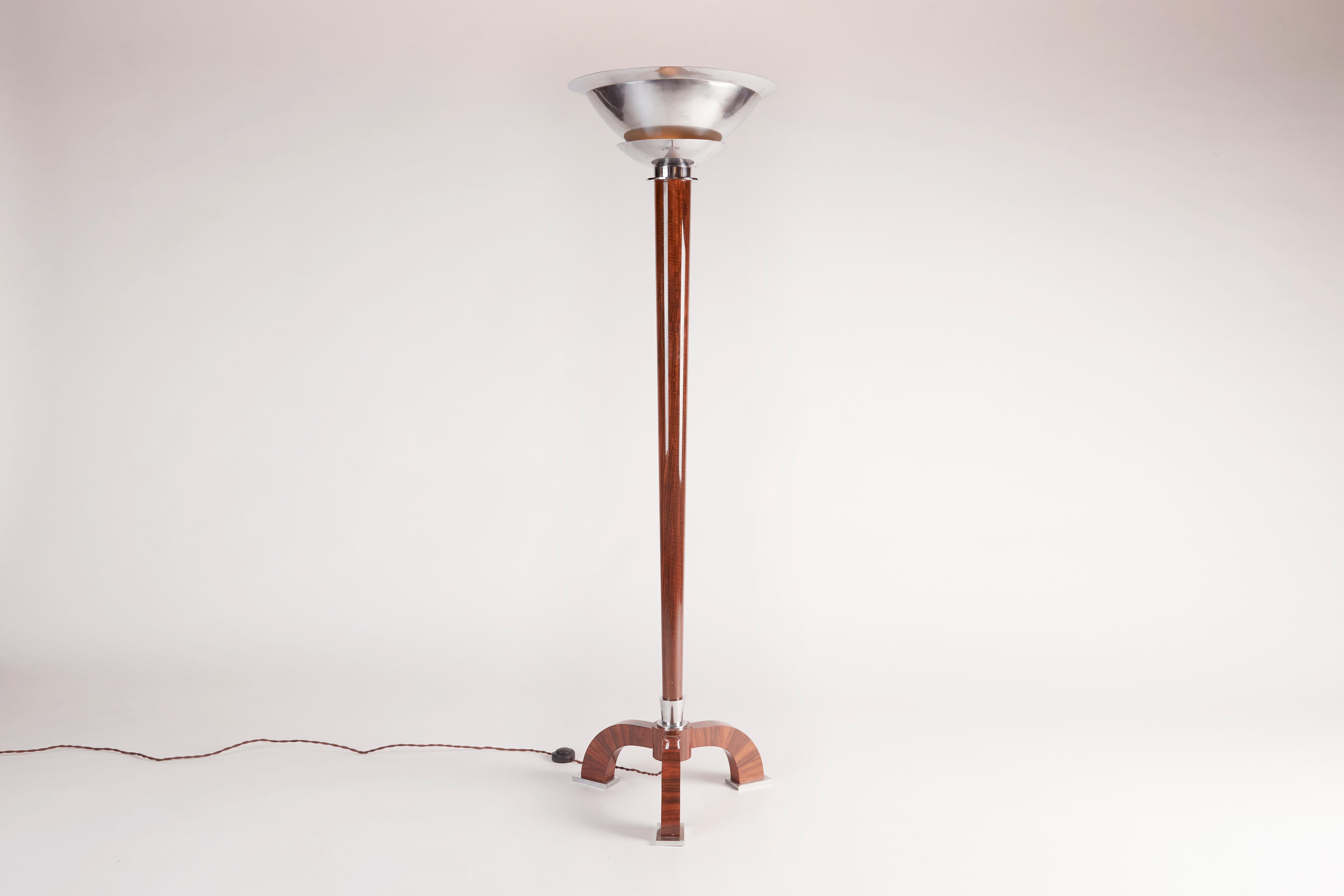 This elegant floor lamp, a design from the early 1930s by Jules Leleu, features a tapered stem in walnut--a long vertical element that unites the complementary shapes of the lamp's playful feet and unusually modern chrome-plated shade.

To our