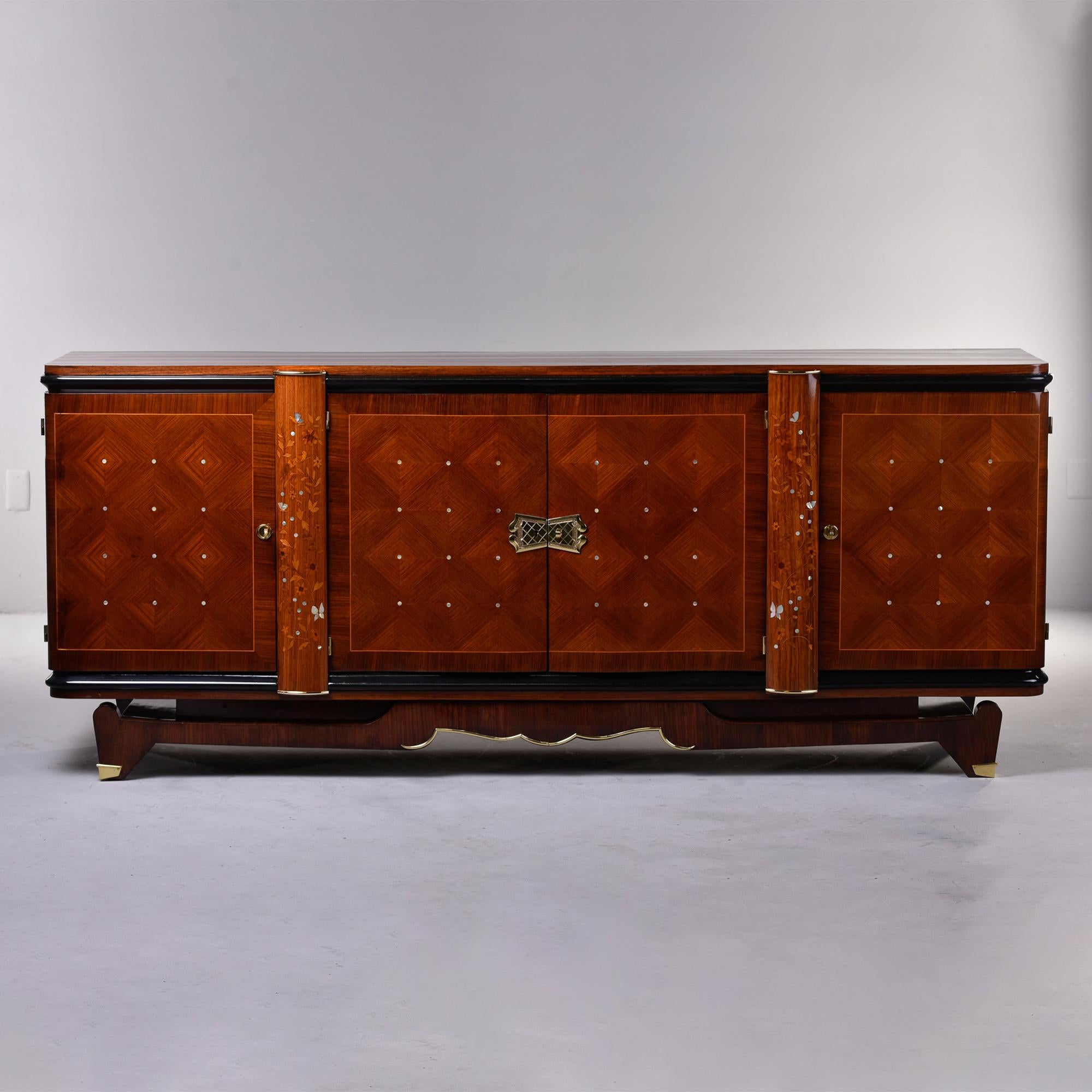 From a Paris estate, this circa 1940s long palisandre French buffet cabinet with extensive wood and mother of pearl inlay is attributed to Jules Leleu. Each side of this piece features a cabinet that opens to storage with a single internal shelf.