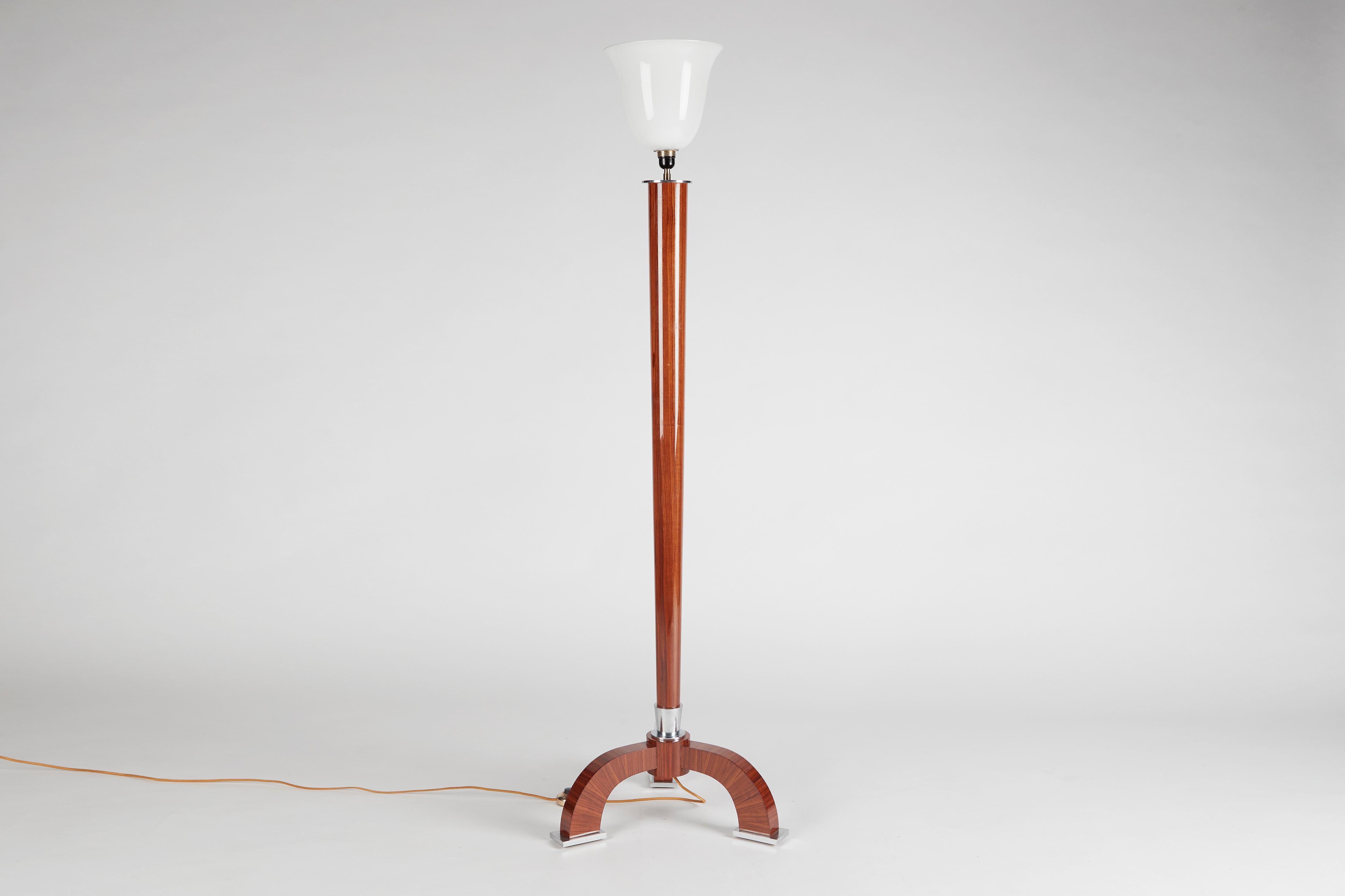 This elegant floor lamp, a design from the early 1930s by Jules ?Leleu, features a tapered stem in walnut veneer--a long vertical element that unites the playfully complementary shapes of the lamp's chrome detailed feet and frosted glass