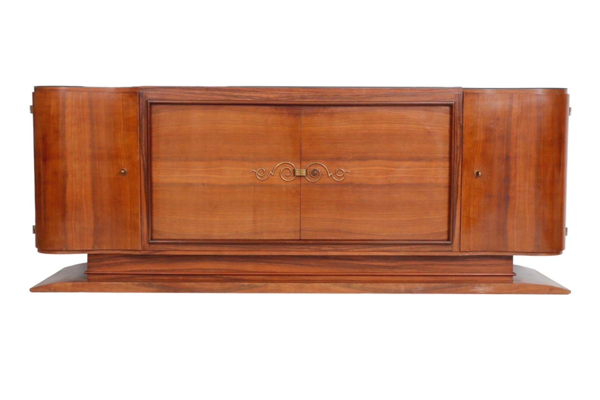 A French Art Deco period sideboard attributed to Jules Leleu. Made of mahogany, it consists of four seperate pieces secured together with bolts. A central cabinet with a beveled frame has book matched cabinet doors decorated with an elaborately