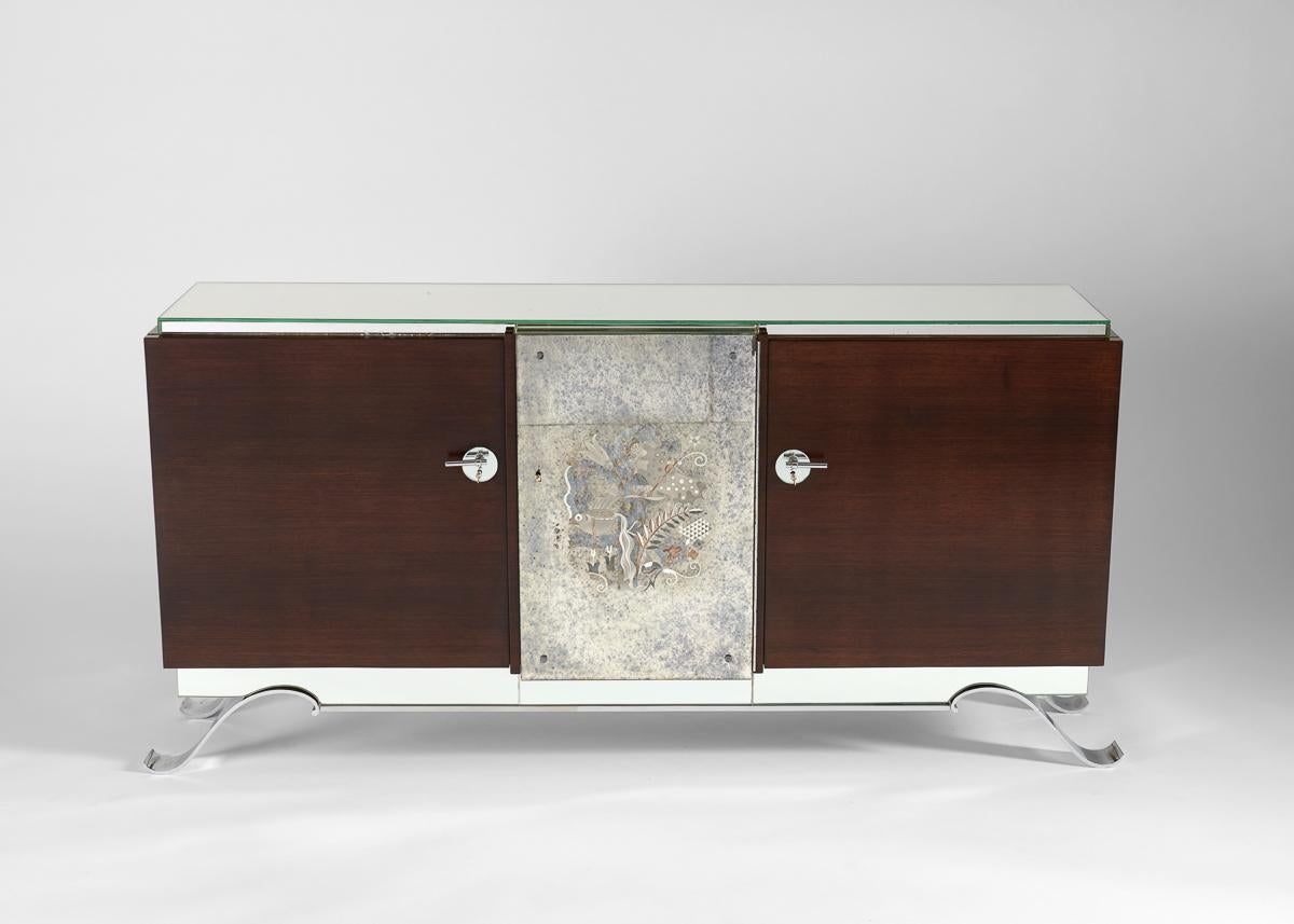 This modernist cabinet in violet wood retains its original central glass églomisé panel depicting lilies, a butterfly, and a fish, and rests on a chrome-plated metal base with curving, ribbon-like legs.  A drawing by Anatole Kasskoff (1898-1978)